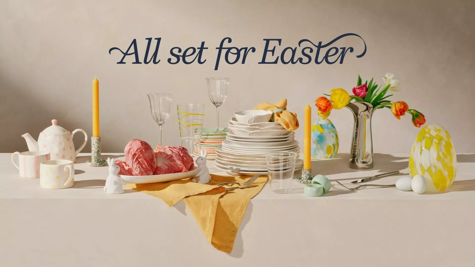 Easter-themed table setting with colourful tulips, elegant crockery, candles, and decorative eggs. 