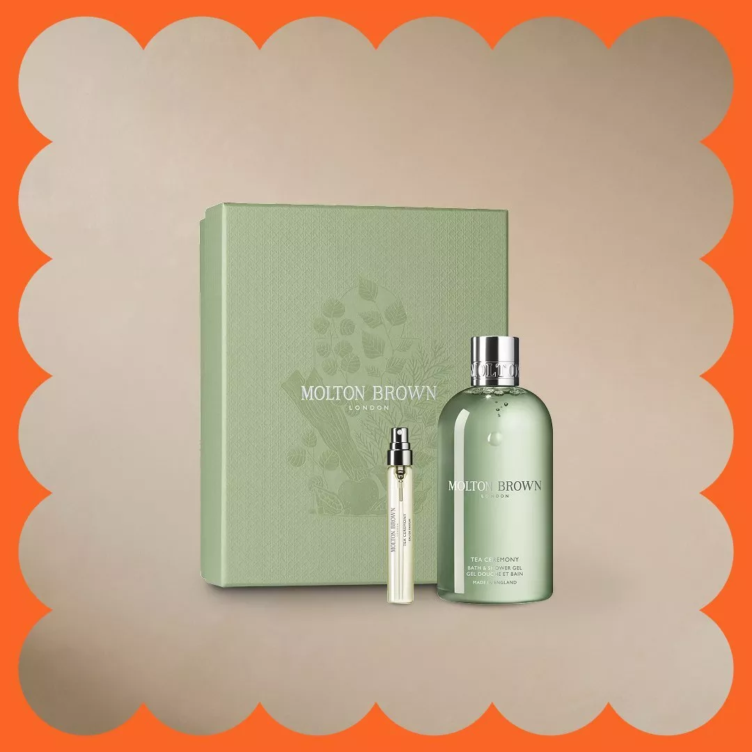 Chanel beauty set with Coco Mademoiselle perfume, pink lipstick, and branded white pouch on a beige background.