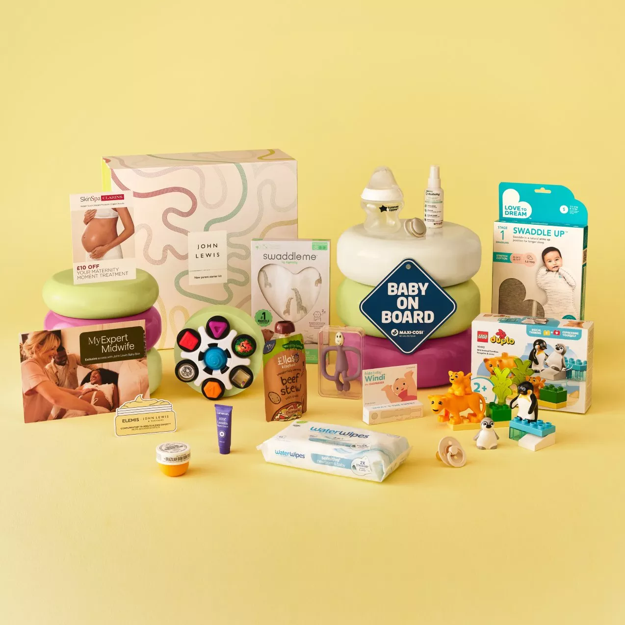 John Lewis baby gift hamper with swaddle, wipes, toys, baby on board sign and LEGO Duplo on yellow background