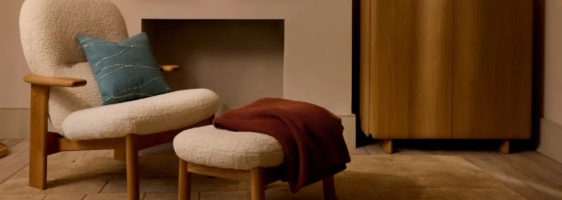 Cosy boucle armchair and footstool with cushion and throw, styled in warm minimalist living room interior