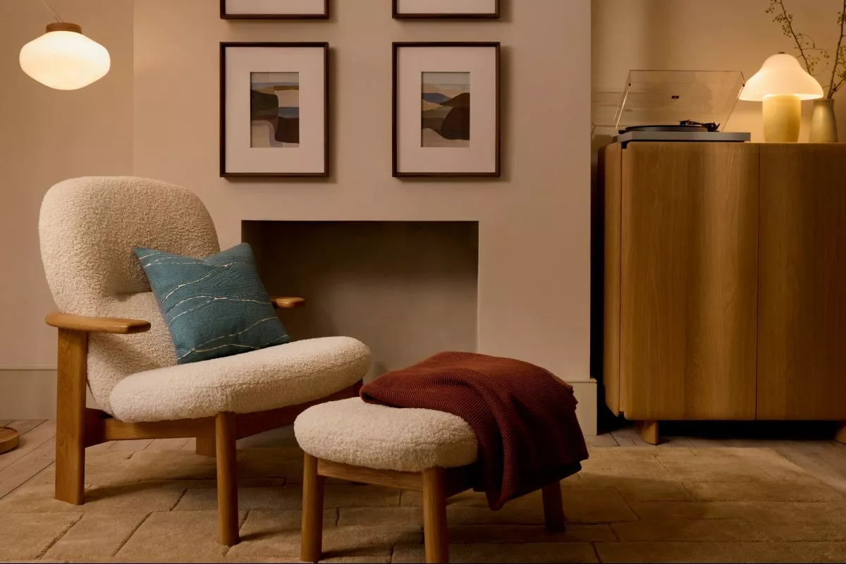 Cosy modern living room with boucle armchair and ottoman, framed art, pendant lights, and turntable cabinet