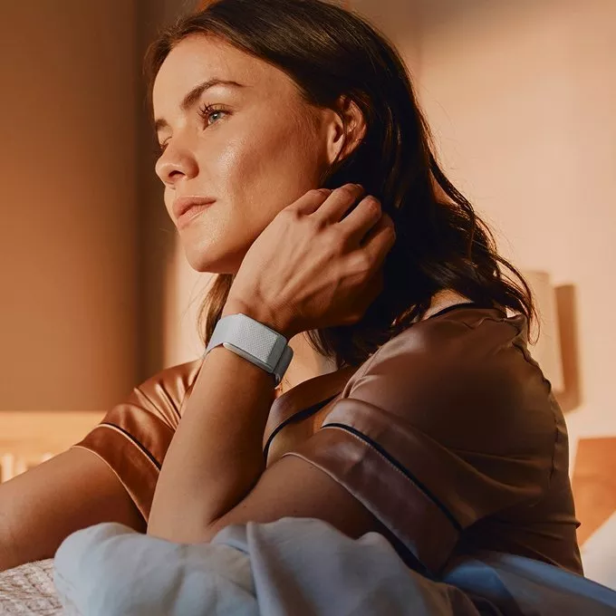 women waking up in bed witha whoop on her wrist