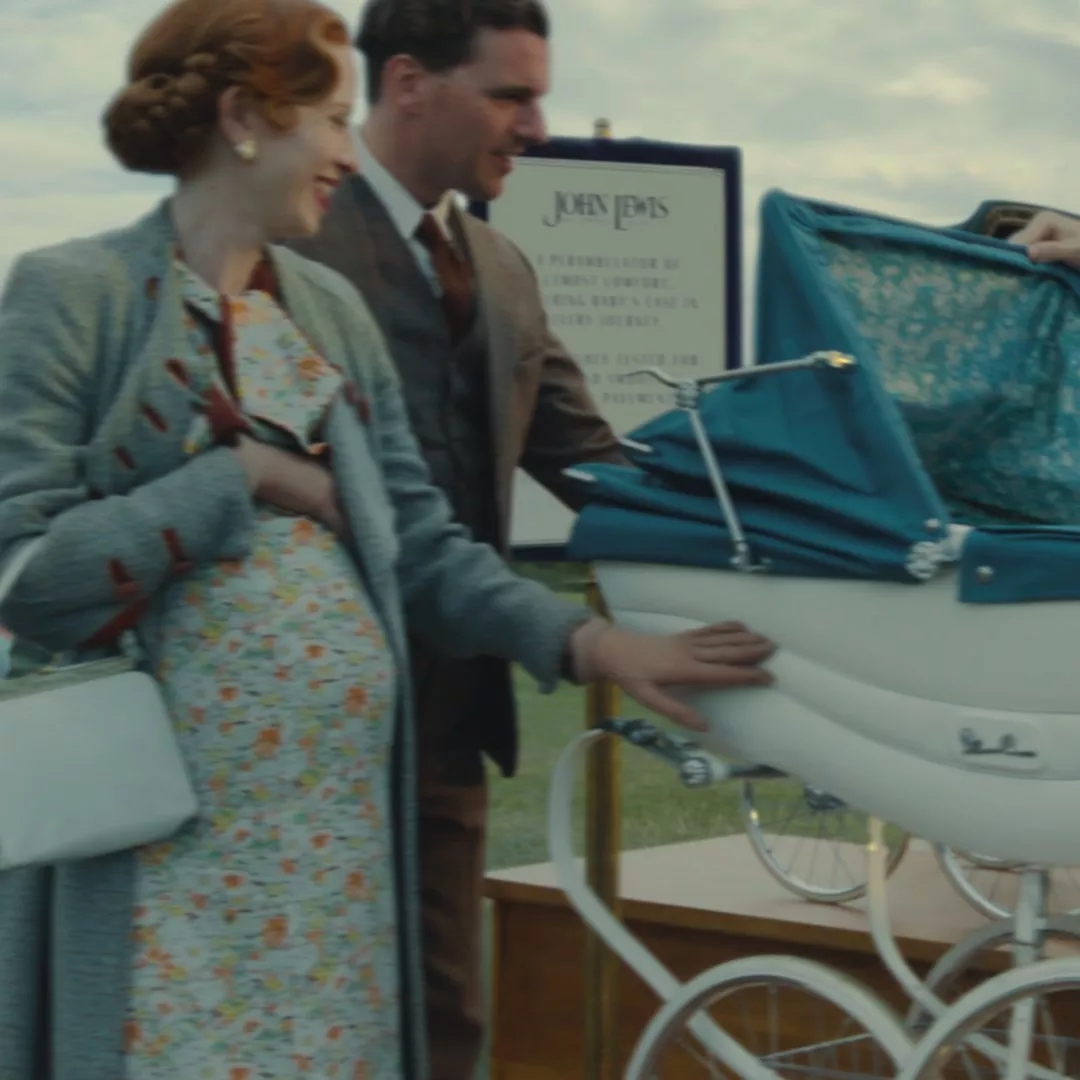 A vintage-style pram with a blue canopy is displayed outdoors. A sign from John Lewis is visible in the background.
