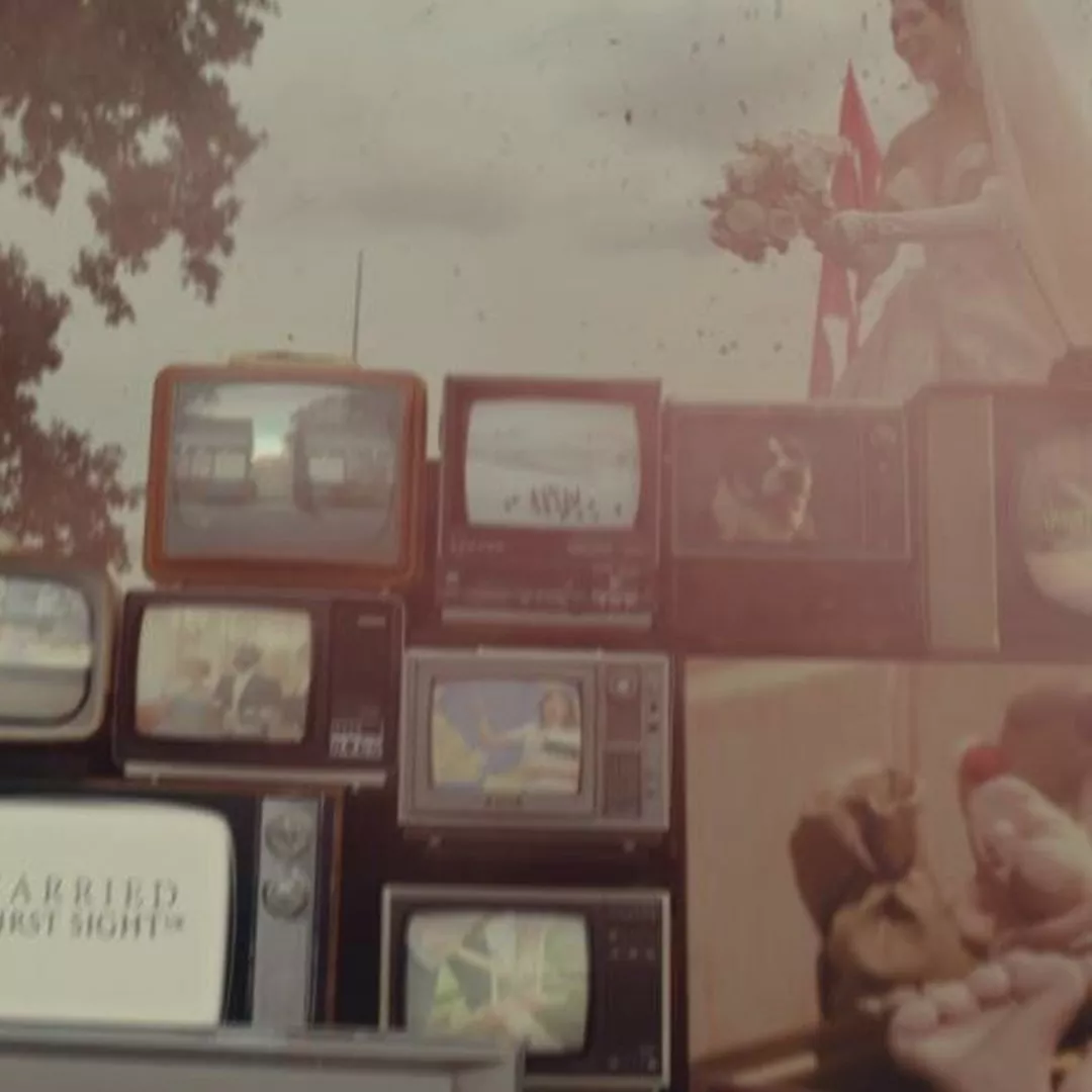 A stack of vintage televisions displays various images, with a bride holding flowers in the background.