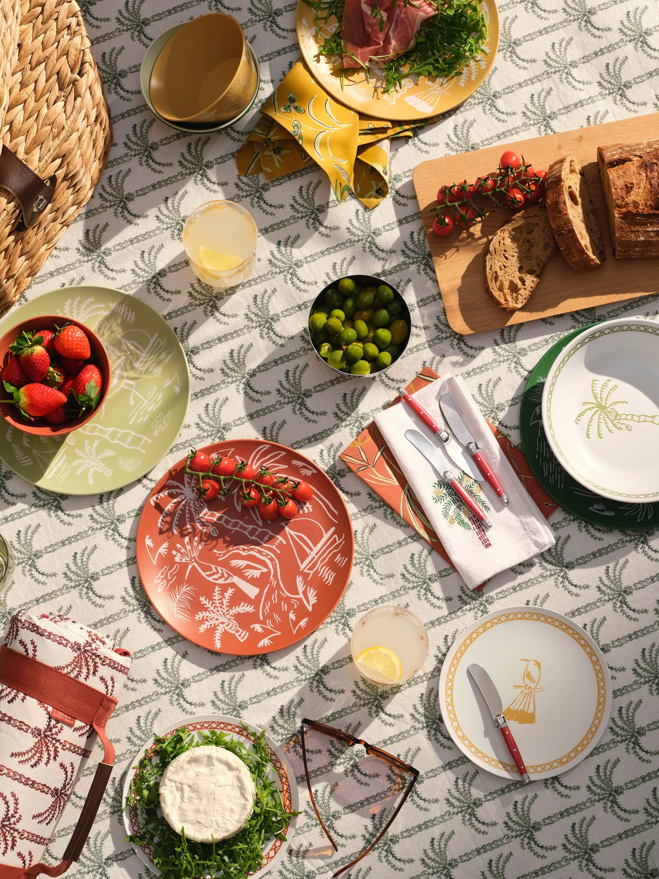 Outdoor dining set up with plates, palm tree table cloth and picnic food
