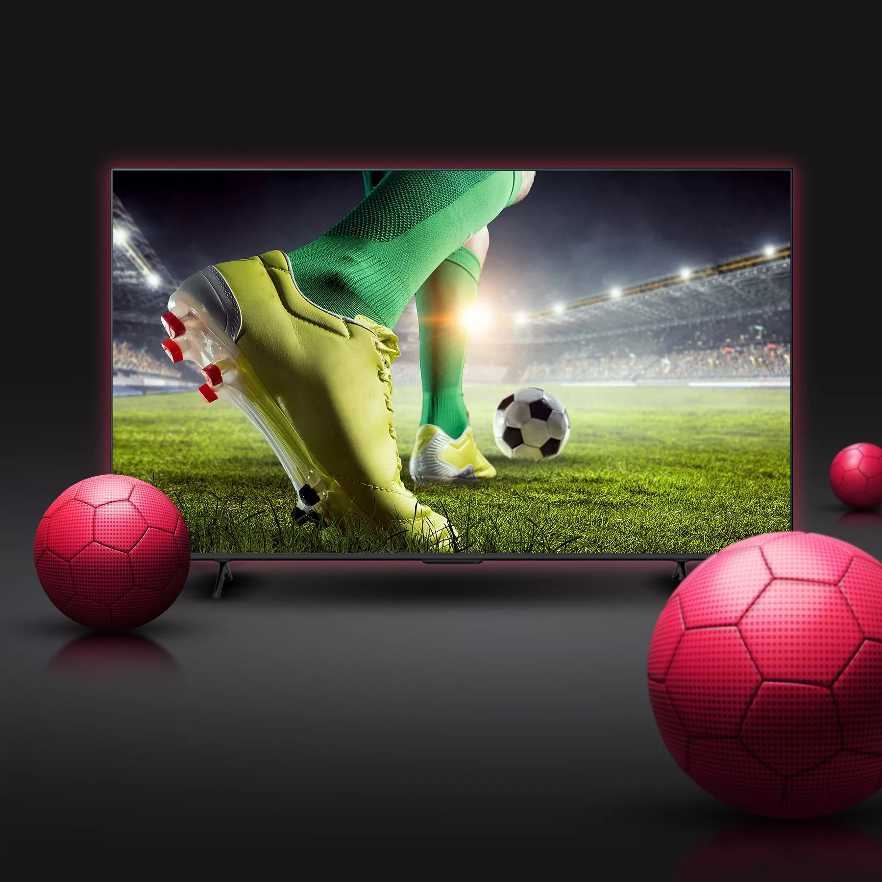Football match on TV screen showing player in green socks and yellow boots on pitch, with balls in foreground