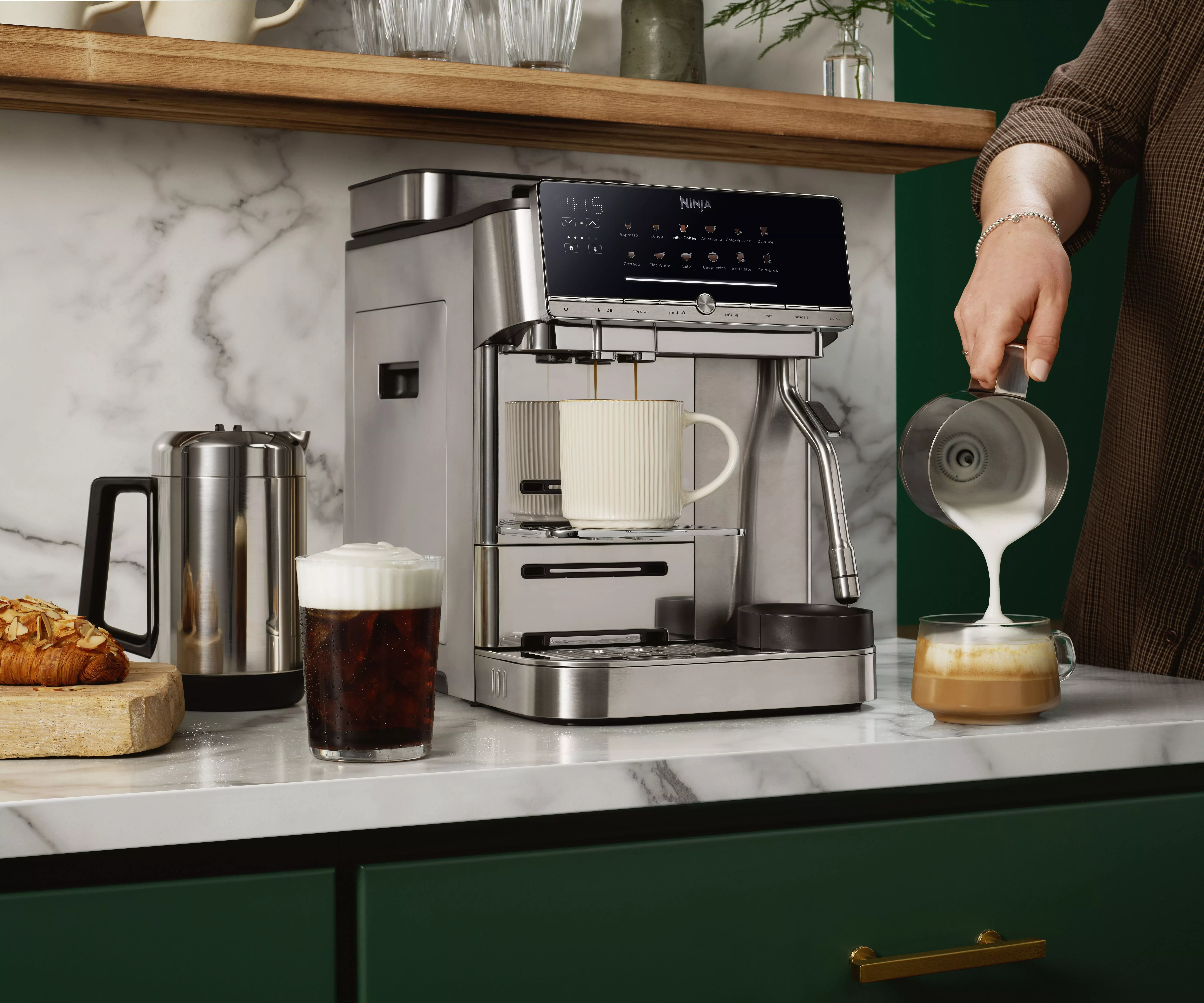 a person pouring milk into a coffee from the milk frother