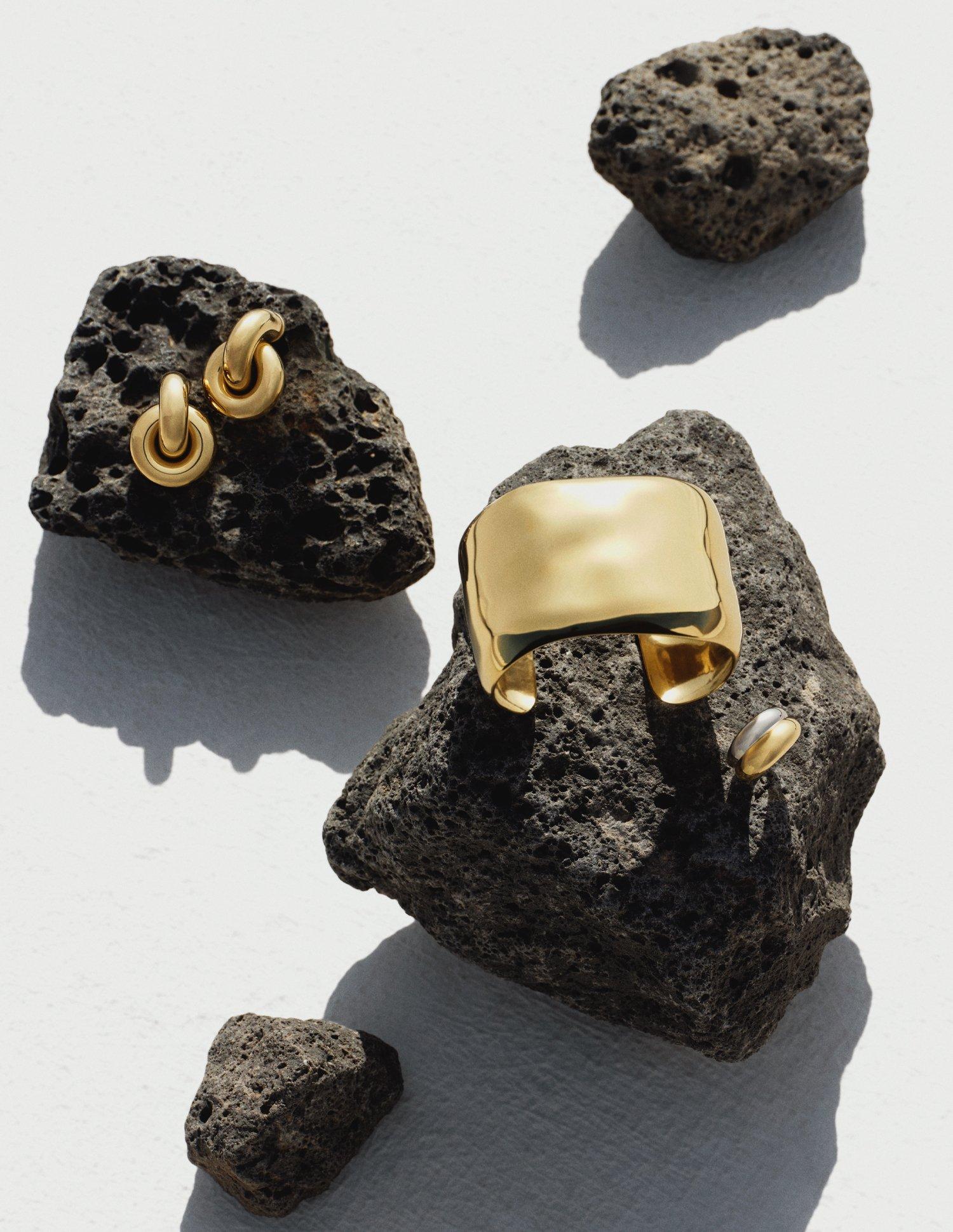 bold gold jewellery lying on volcanic rock