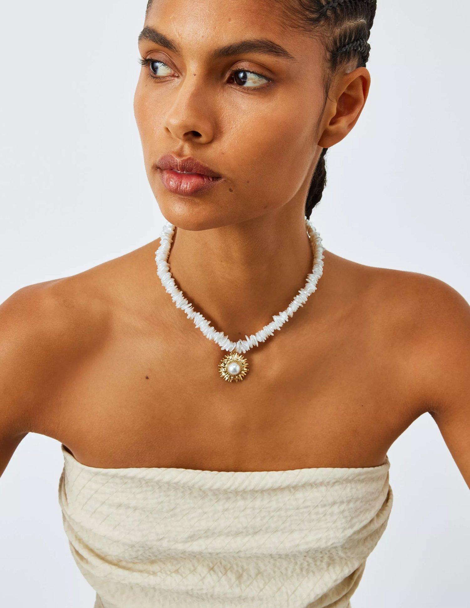women wearinf a thick gold necklace with a pearl at the end