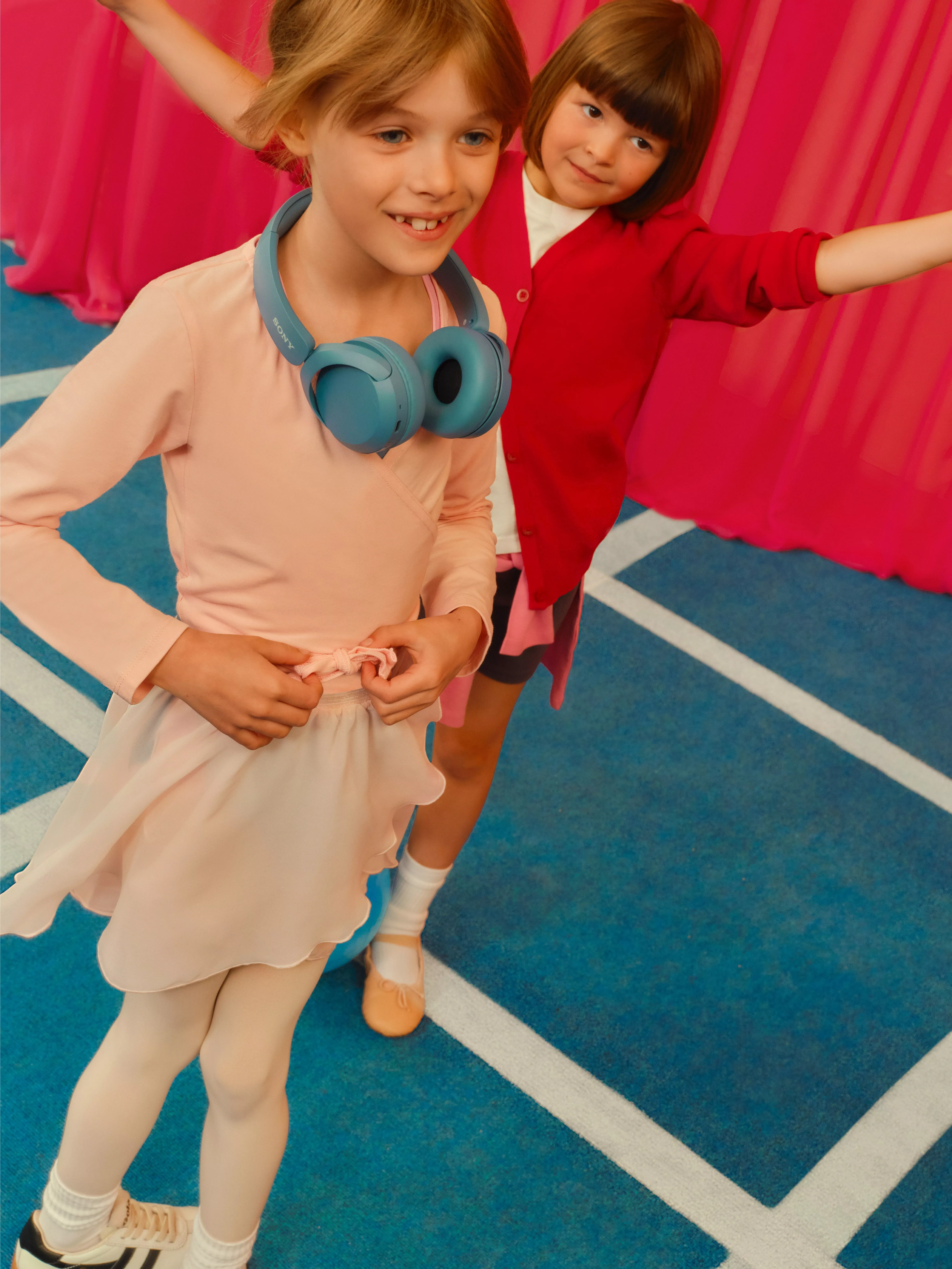 girl with blue over ear headphones around her neck