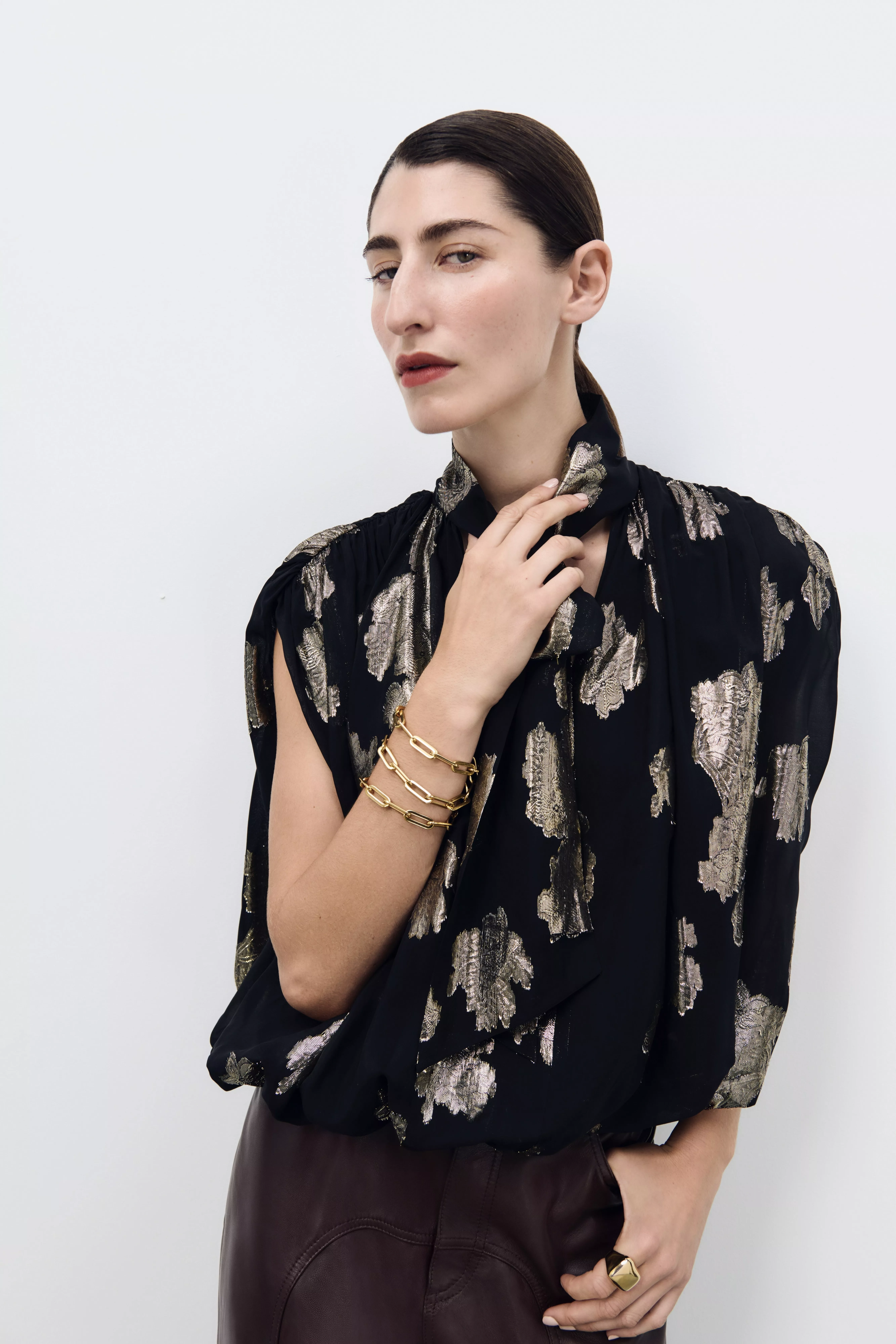 woman in black and gold embellished top with stacked bracelets