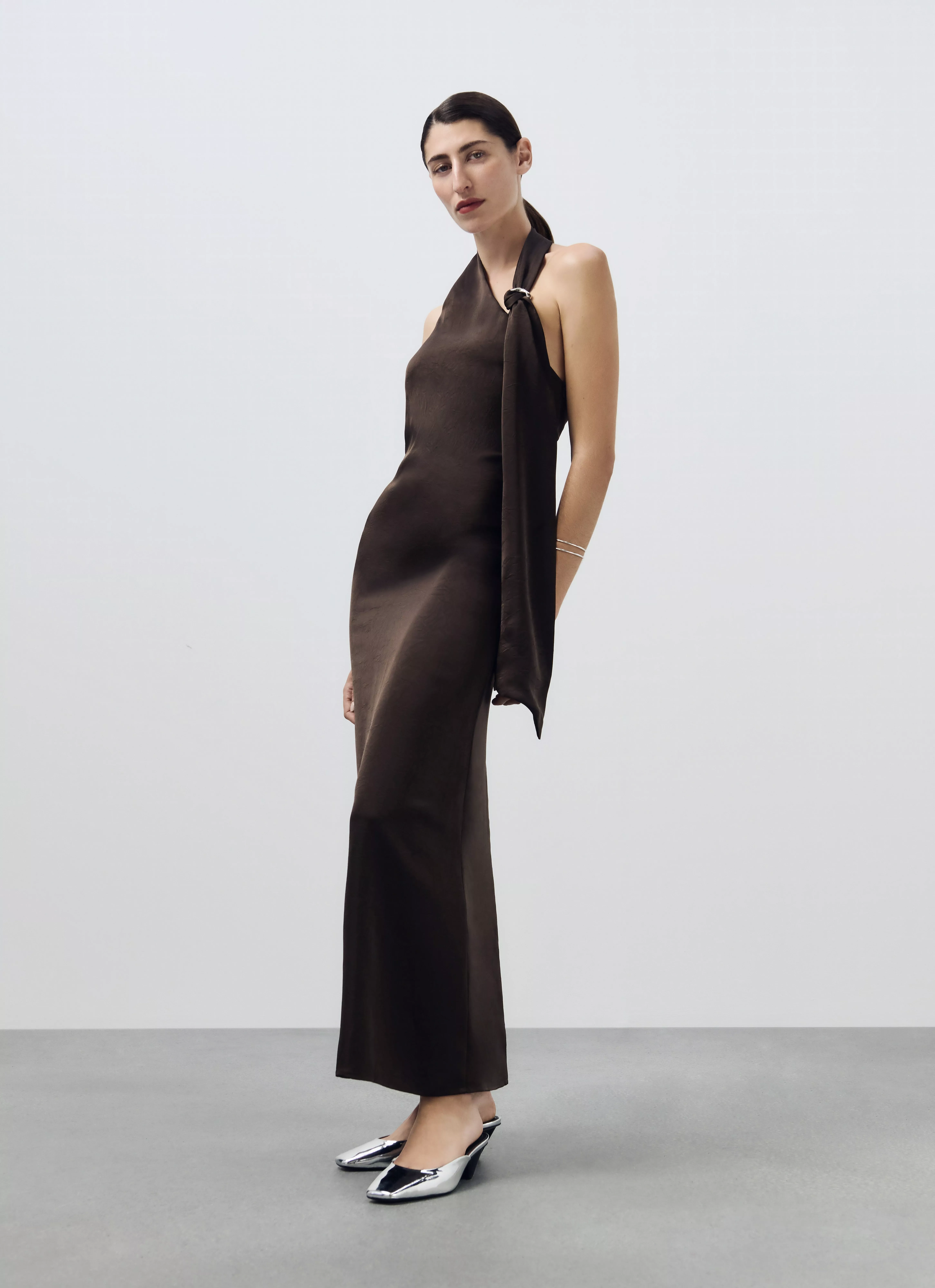 woman in brown halterneck maxi dress with silver pointed heels