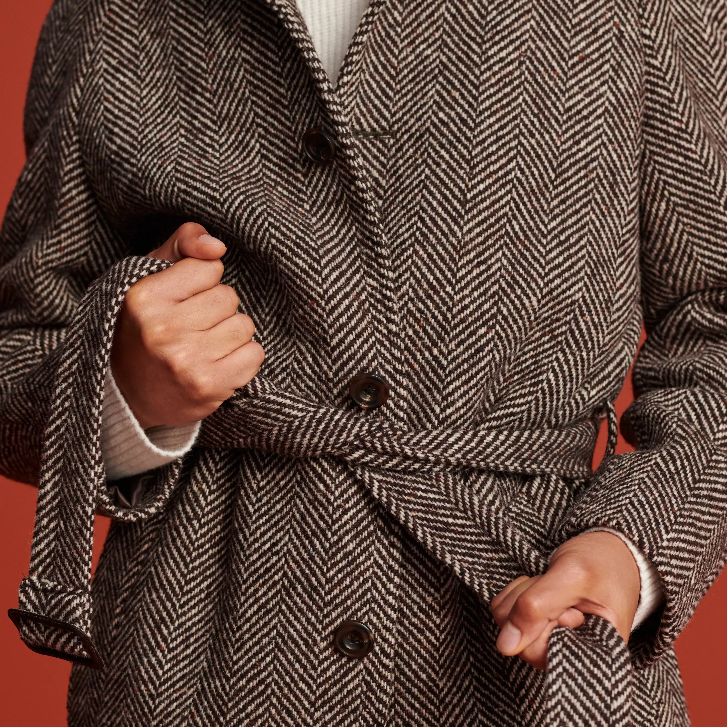 person tying the belt of their coat