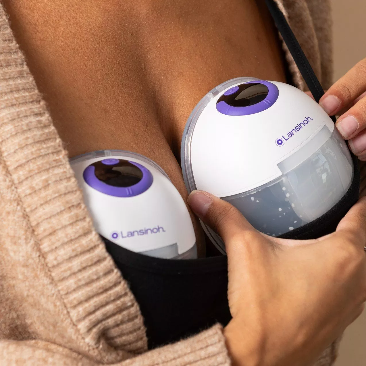 Hands adjusting Lansinoh wearable breast pumps in a nursing bra, discreet electric pumping for breastfeeding mums