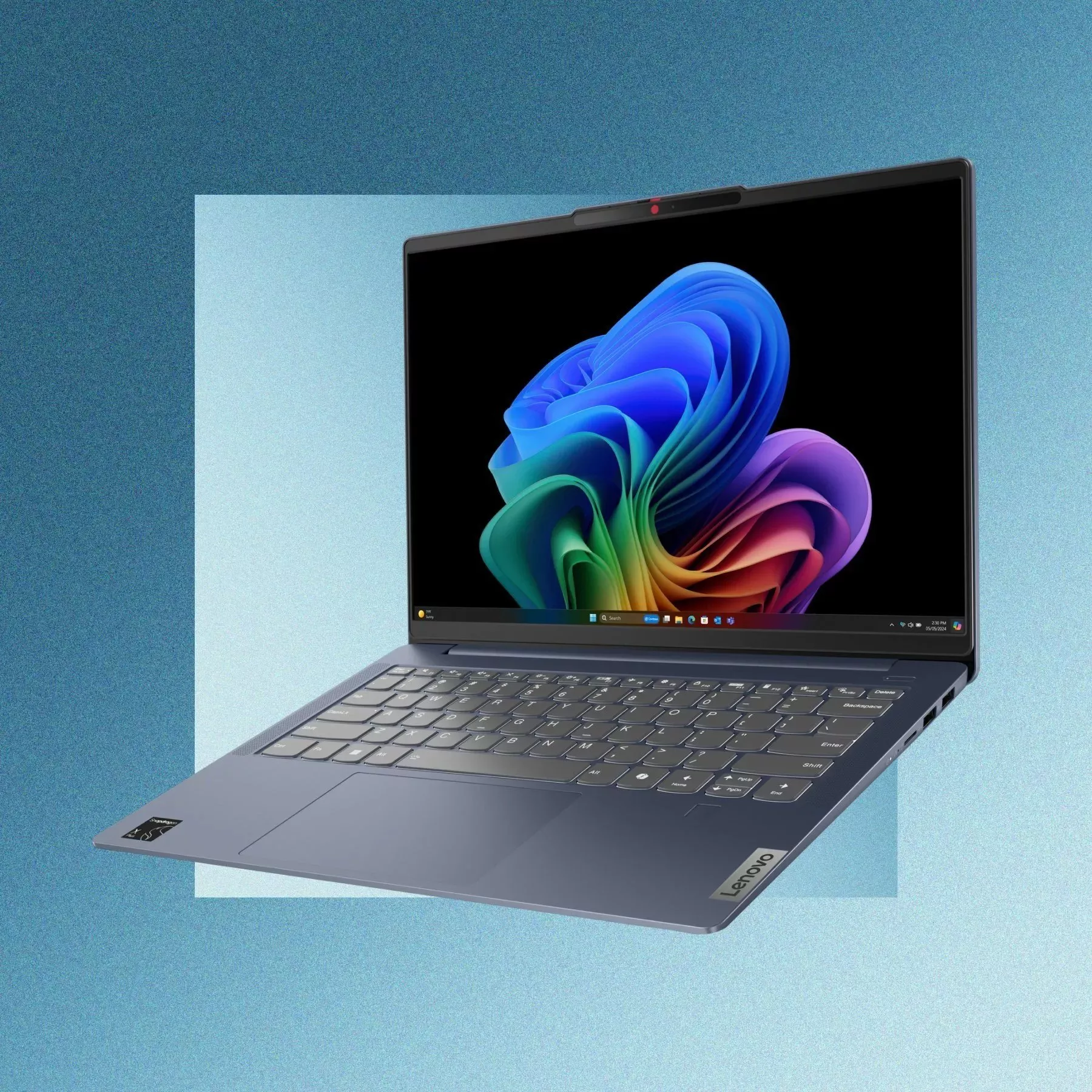 Lenovo laptop with Windows 11 wallpaper on screen, slim grey notebook computer on blue background
