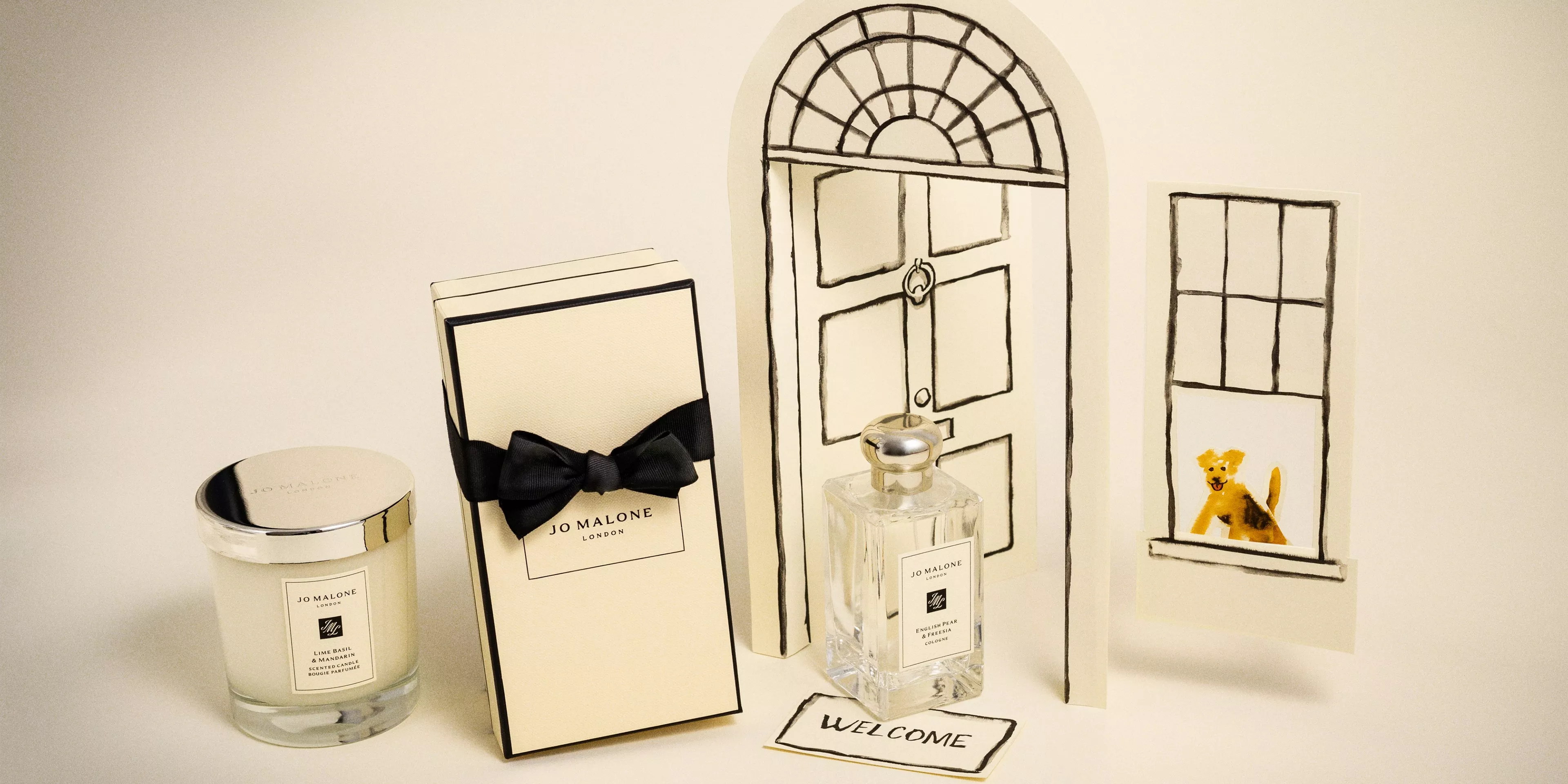 Jo Malone London candle, gift box and English Pear & Freesia cologne beside illustrated door and window scene