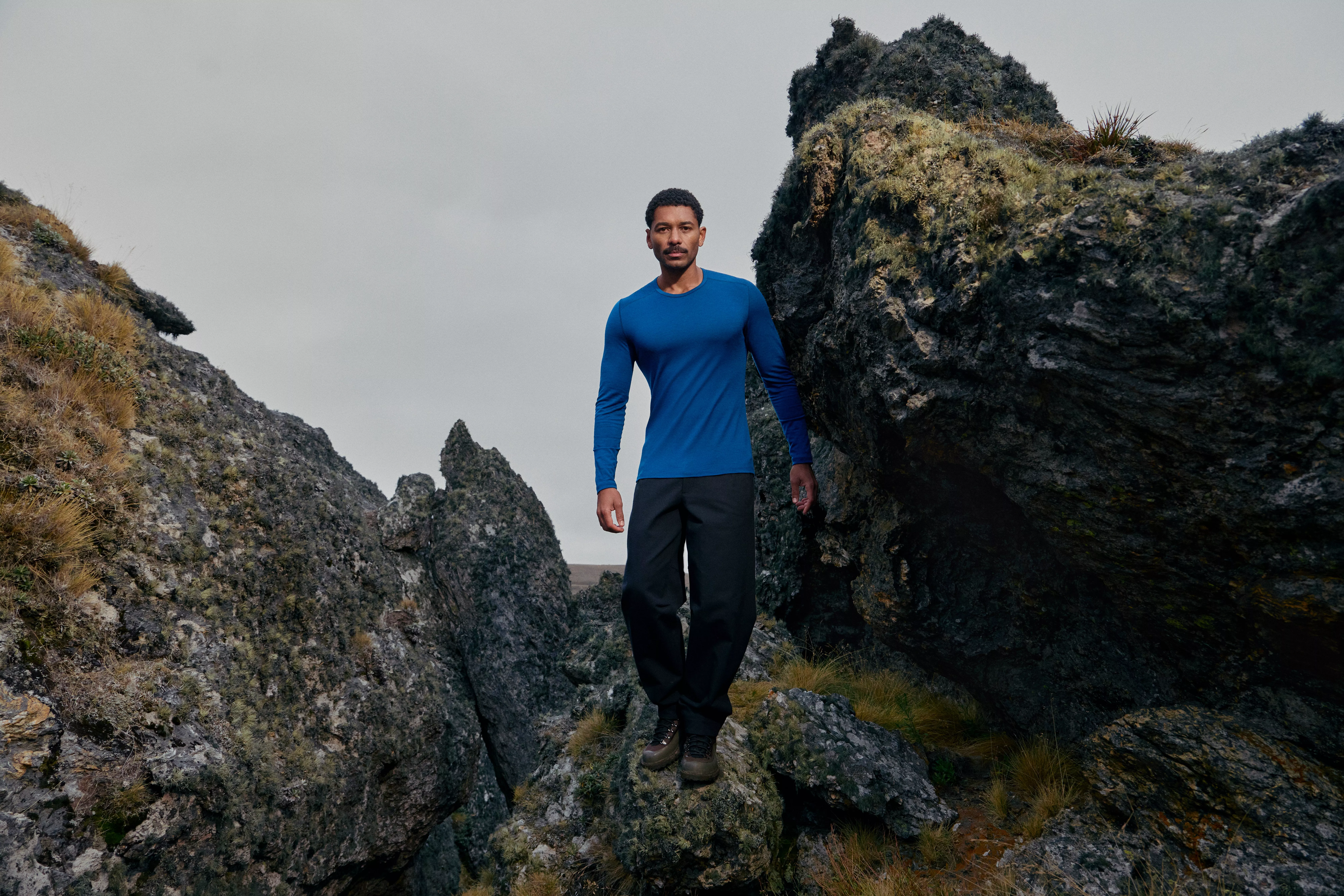 man hiking wearing hiking boots, trousers and a long sleeve blue top