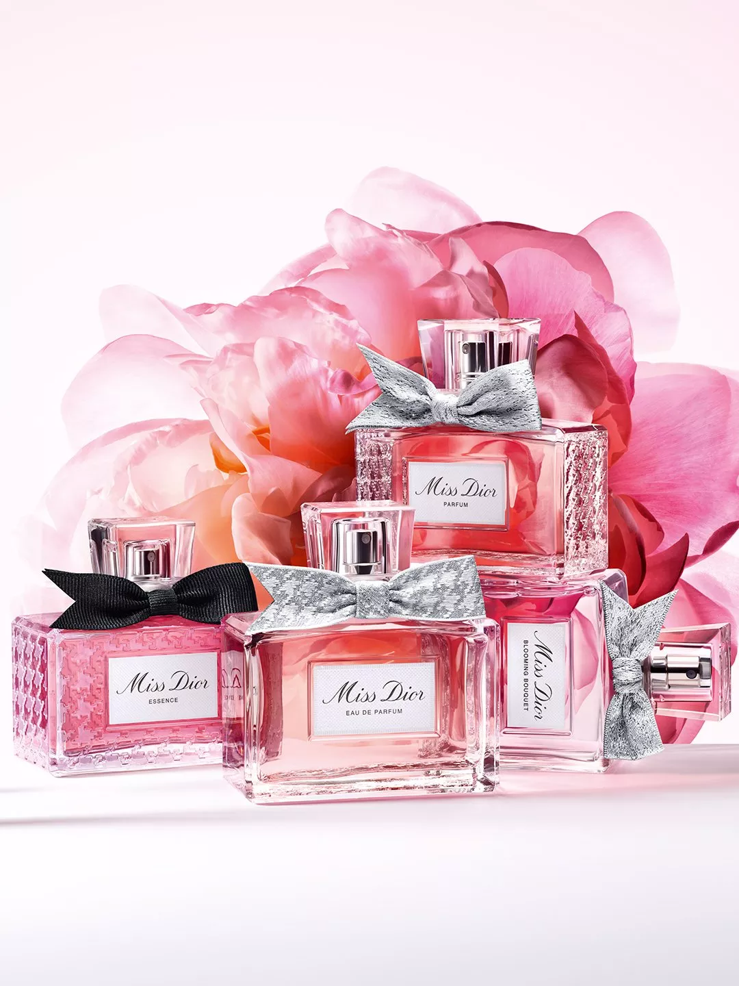 Miss Dior perfume bottles with silver bows and pink floral backdrop, luxury fragrance product photography