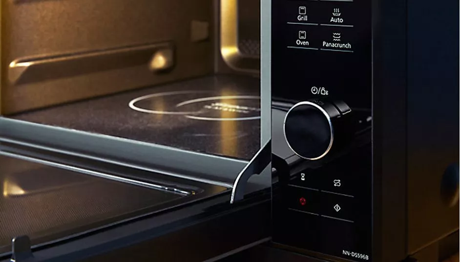 Close-up of modern microwave oven interior and control dial, showing grill, oven and auto cooking settings.