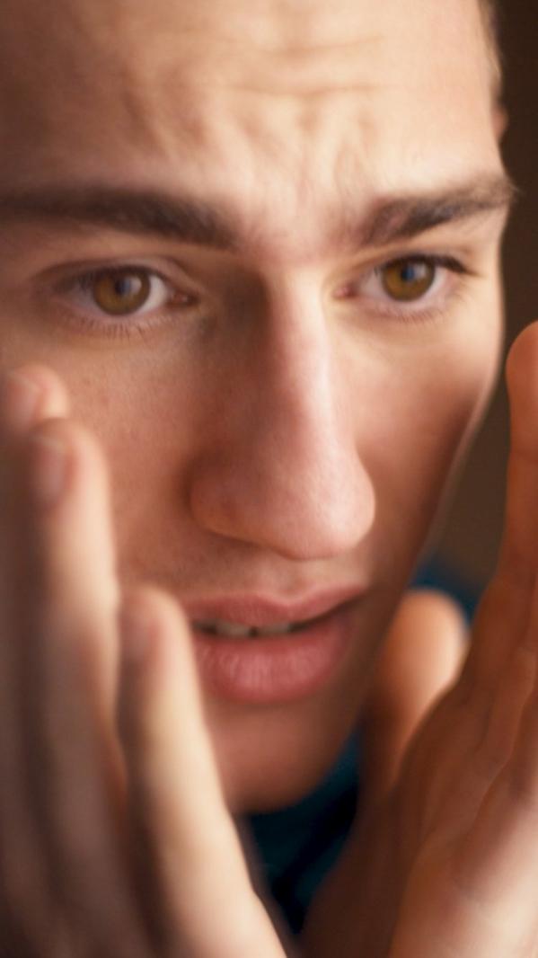 Close-up portrait of a young man holding his face, concerned expression watching the football