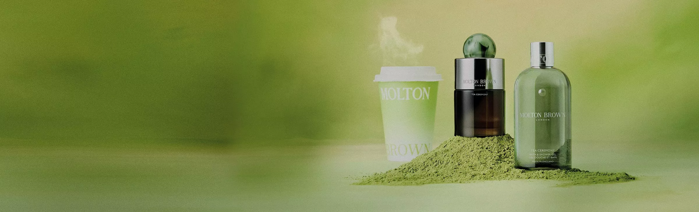 Molton Brown products on a green background, with a steaming cup and a pile of green powder, creating a fresh look.