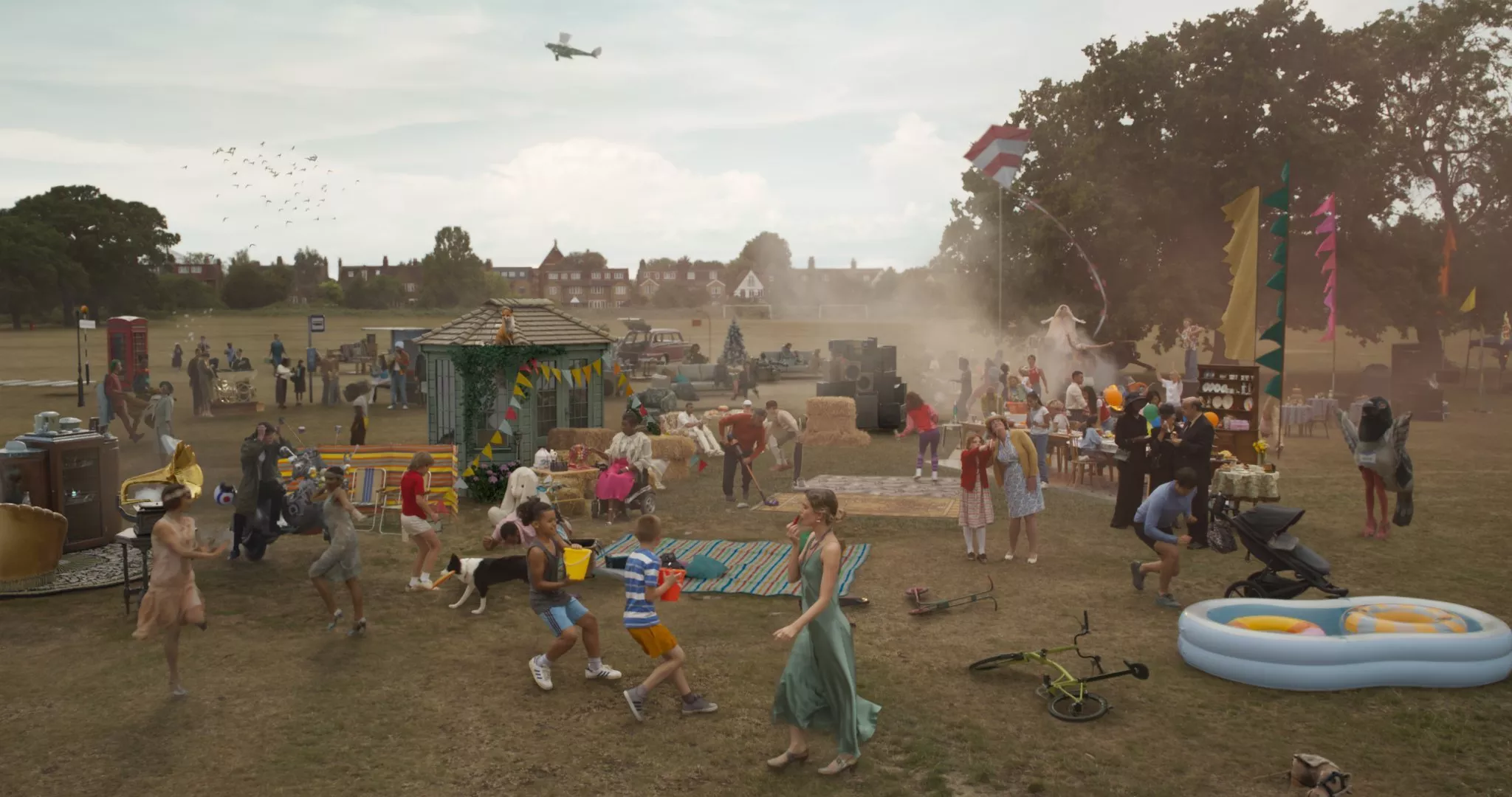 An outdoor gathering with people in festive attire, surrounded by decorations and activities. Text reads "THEN. NOW. ALWAYS."