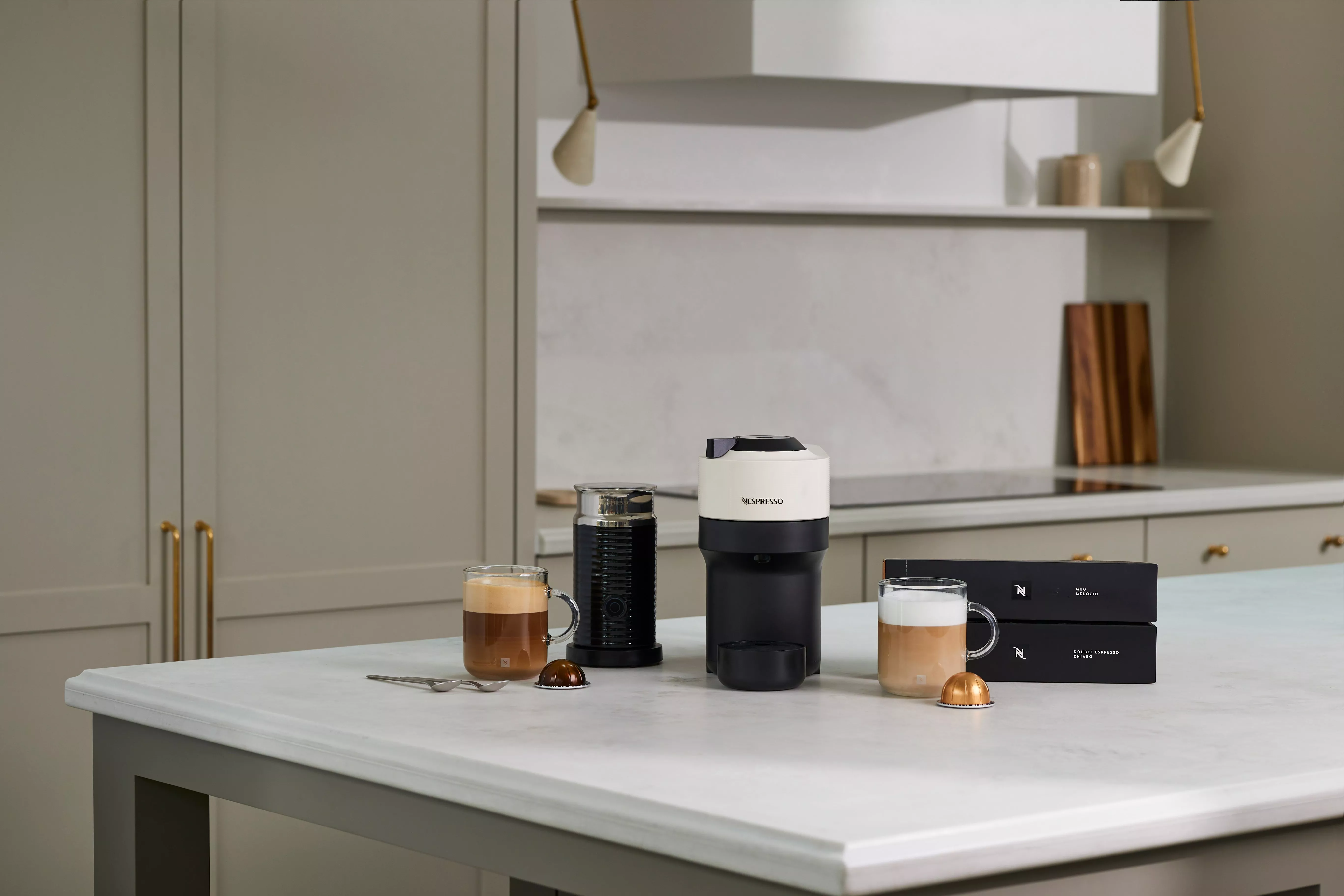 Nespresso Vertuo, milk frother, glass mugs and capsules displayed on a kitchen counter