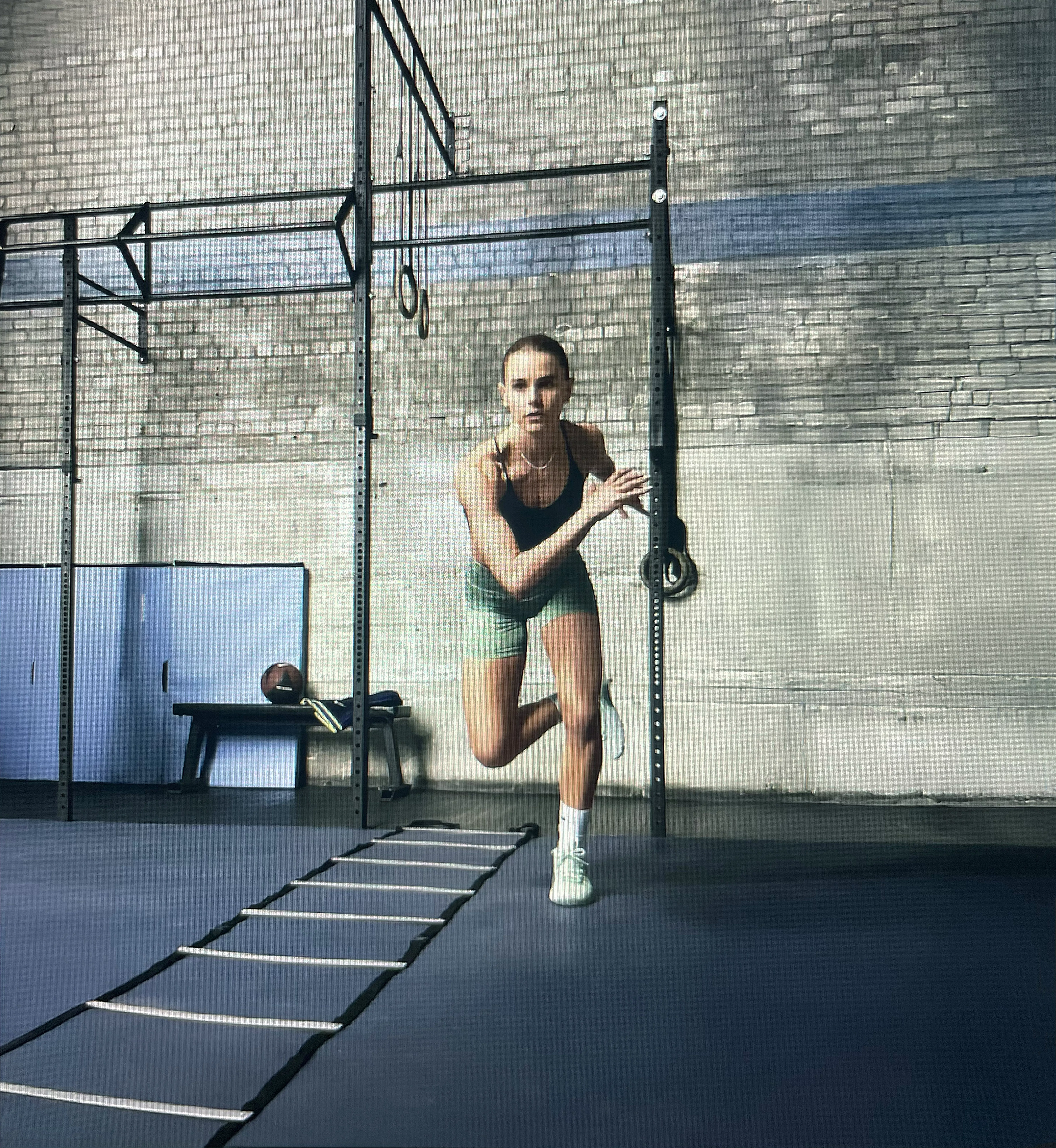 Female athlete doing agility ladder drills in a gym, speed and footwork training for fitness and conditioning