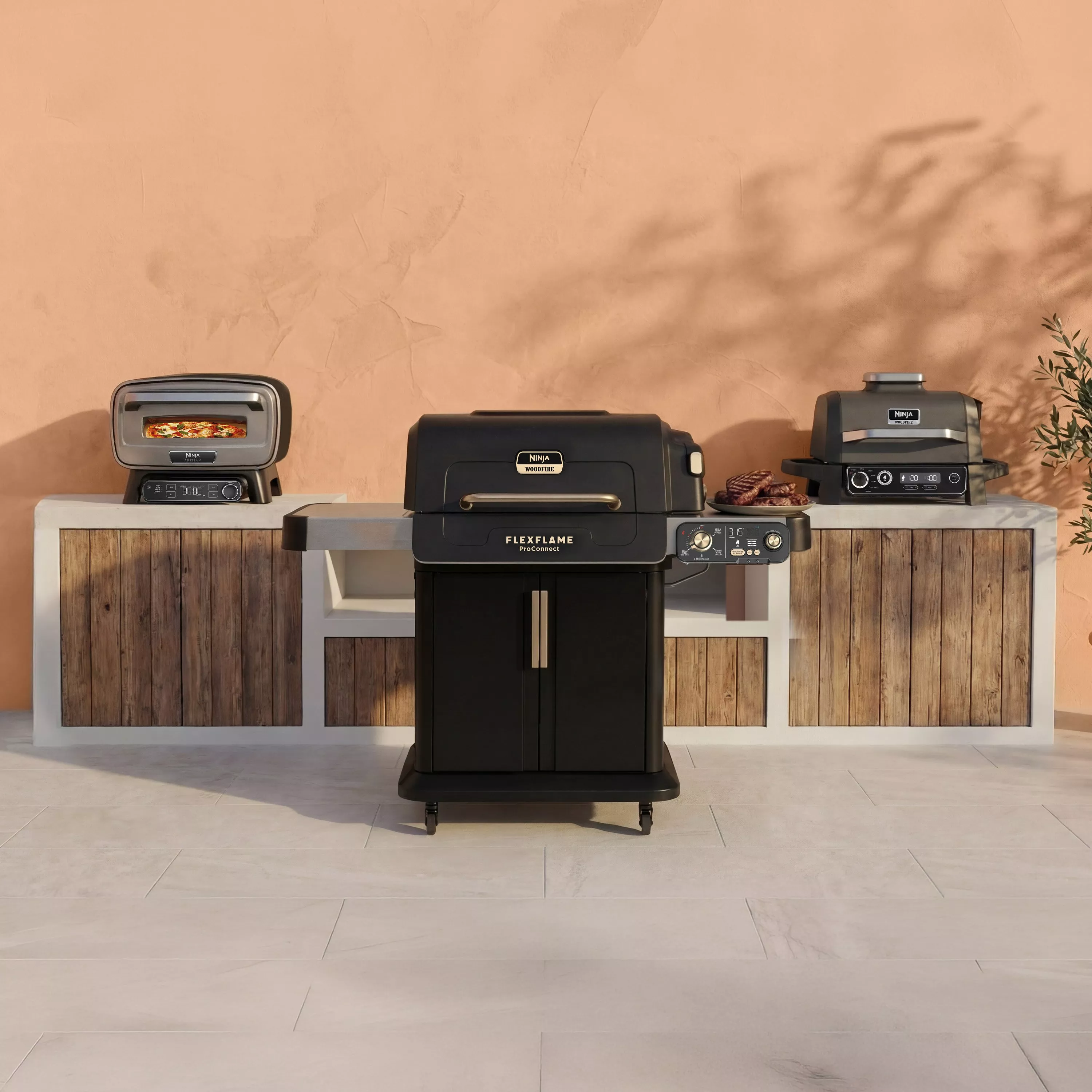 Ninja Woodfire outdoor electric BBQ grill and pizza oven range on patio counter, with steaks and pizza cooking