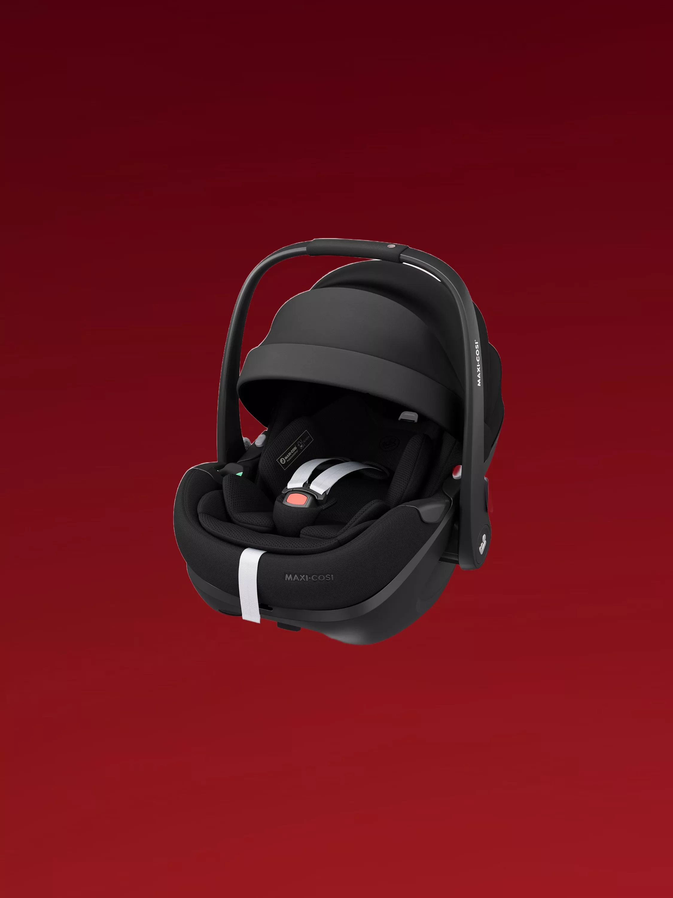 Maxi-Cosi black infant car seat carrier with safety harness and canopy, isolated on red background