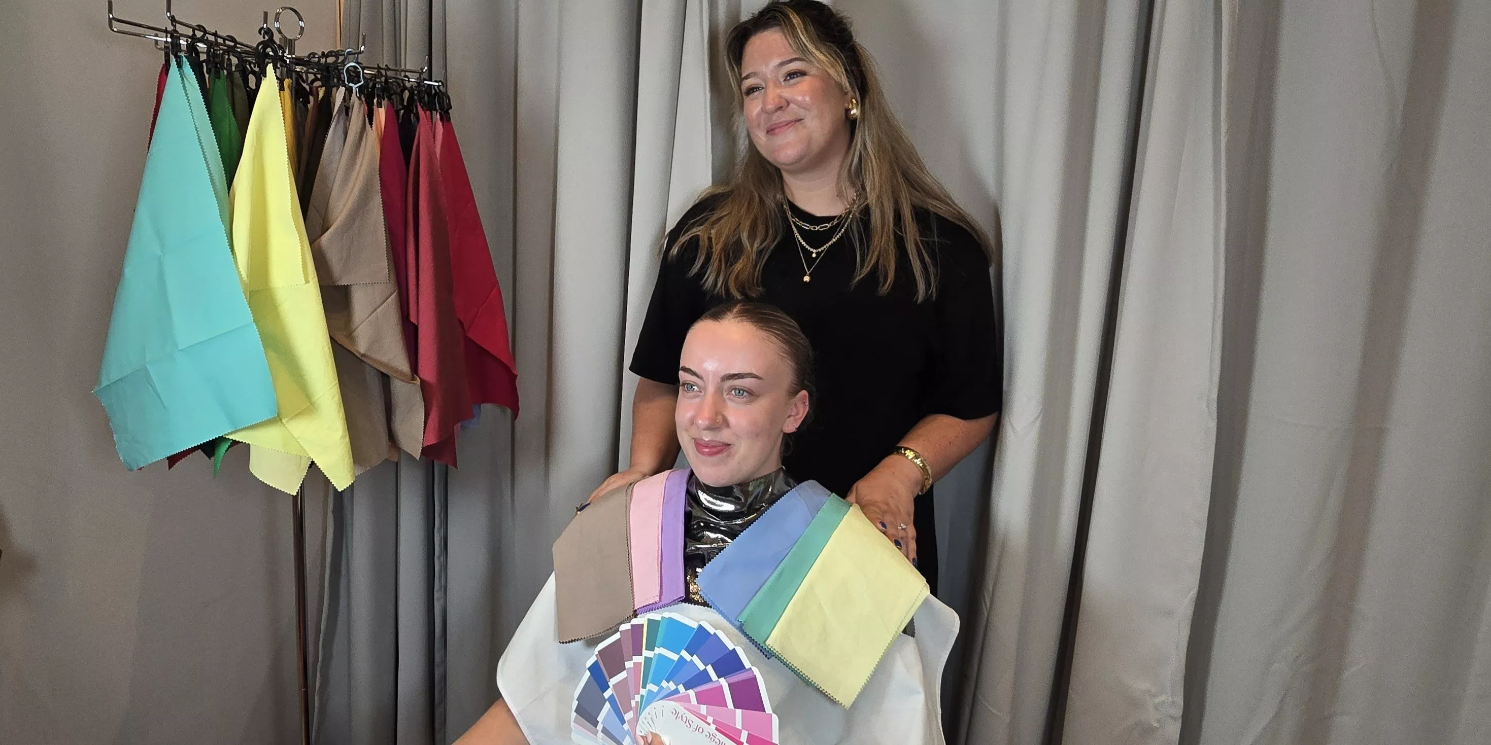 Personal colour analysis consultation with stylist draping fabric swatches and colour fan over client