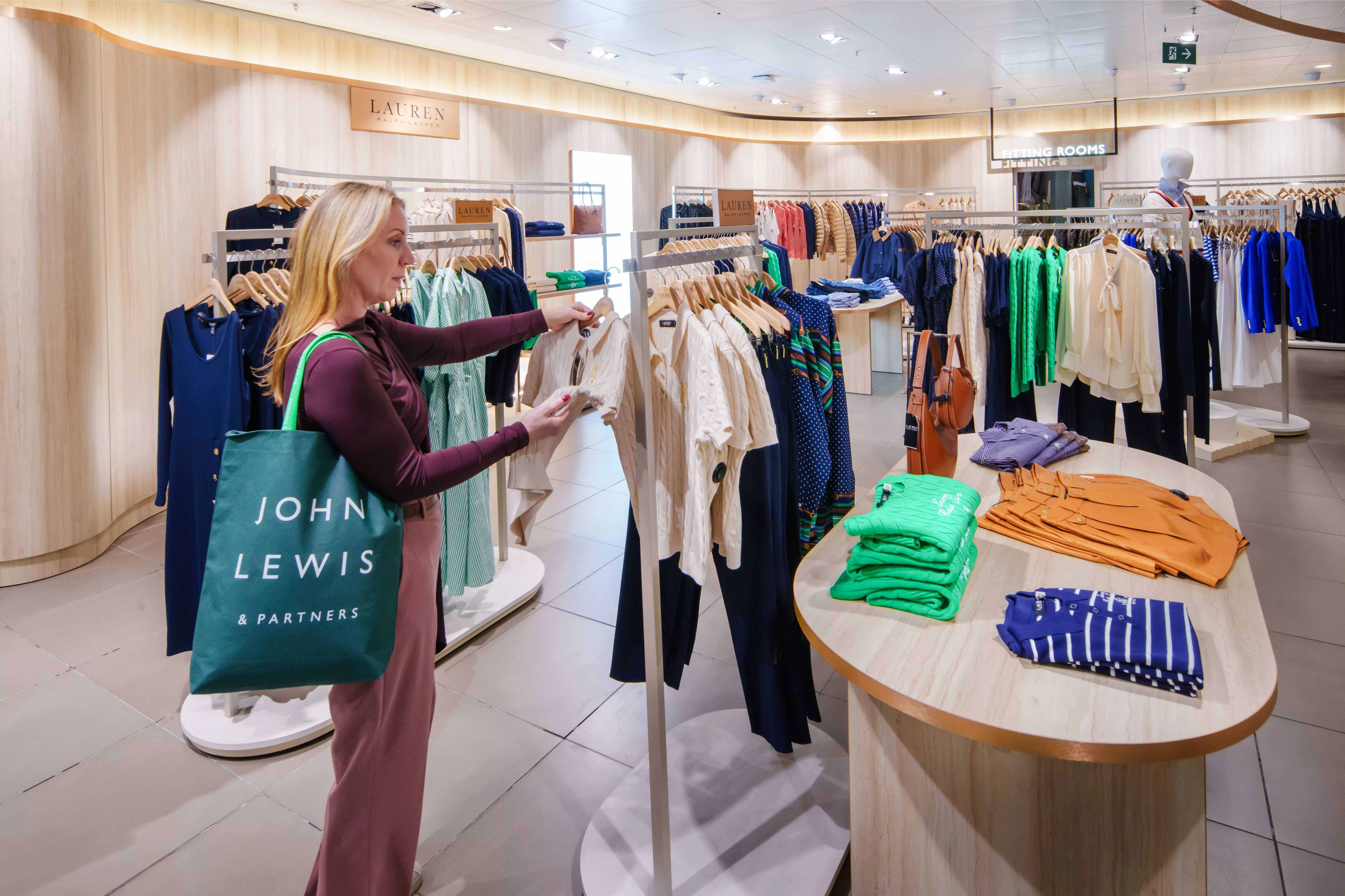 customer carrying a John Lewis tote bag, looking through a rail of clothes