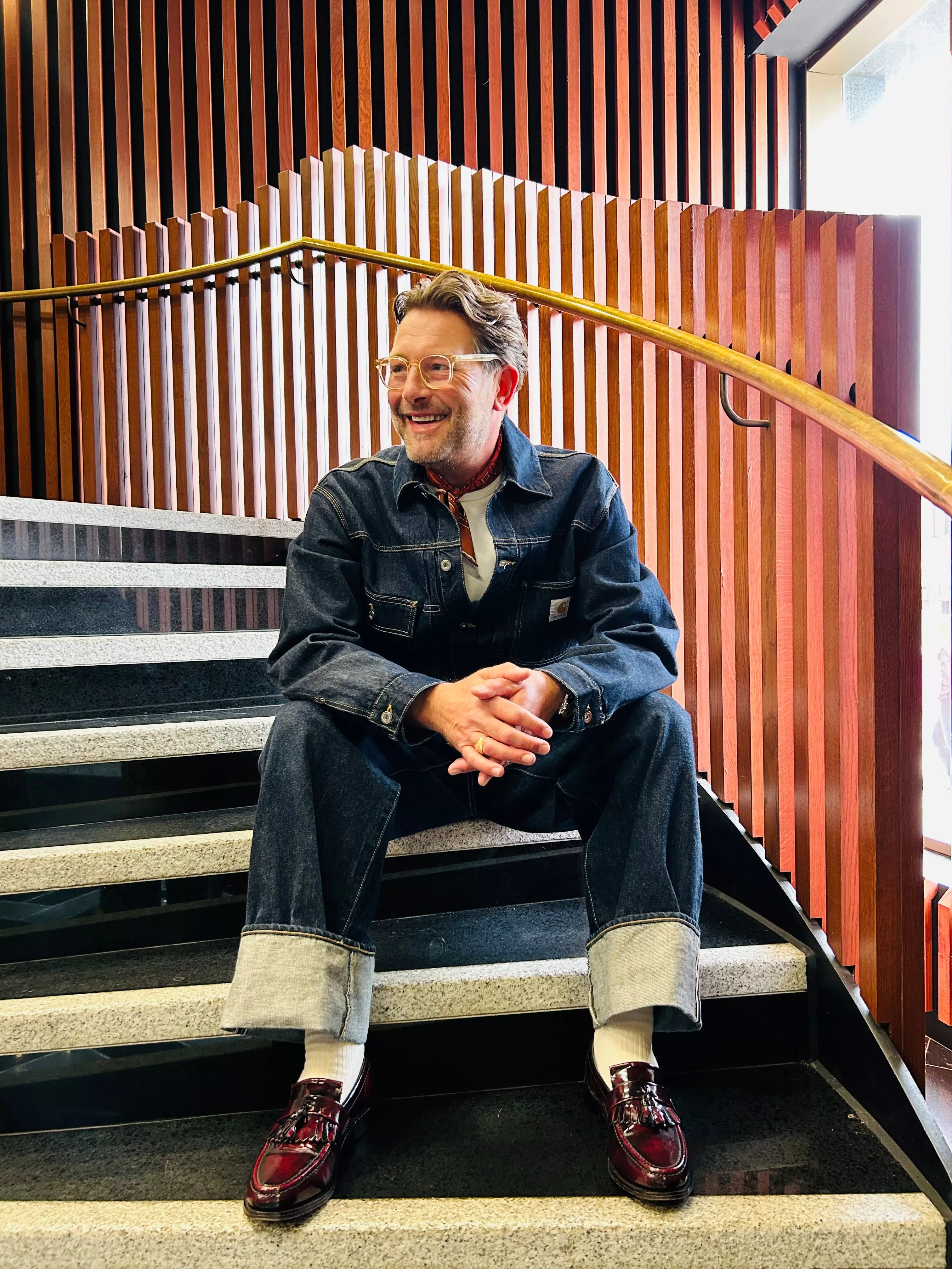 Stylist wearing a denim jacket, white shirt, blue jeans and burgundy loafer shoes