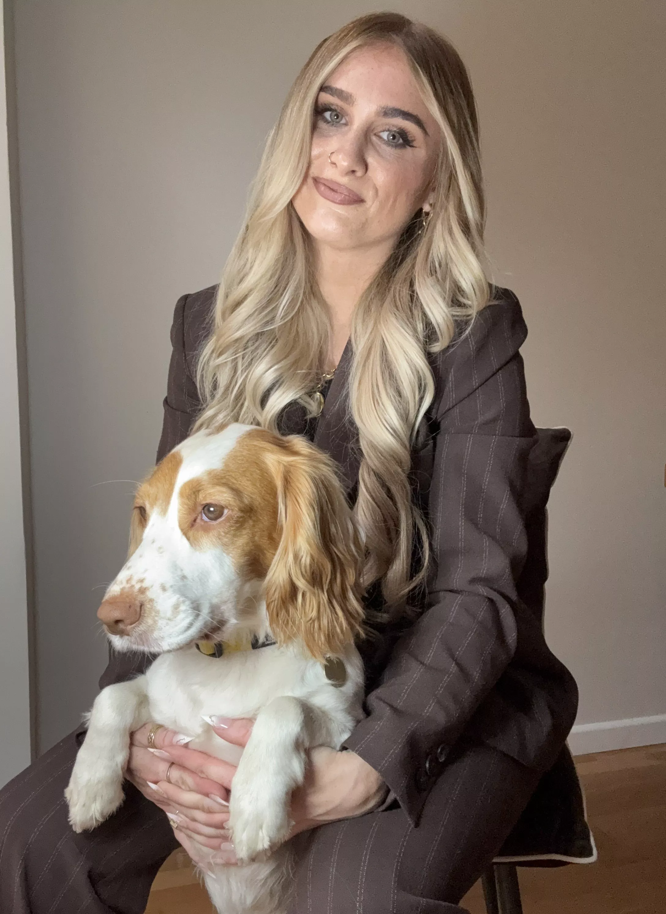Stylist wearing a brown pinstripe trouser suit, cuddling a dog