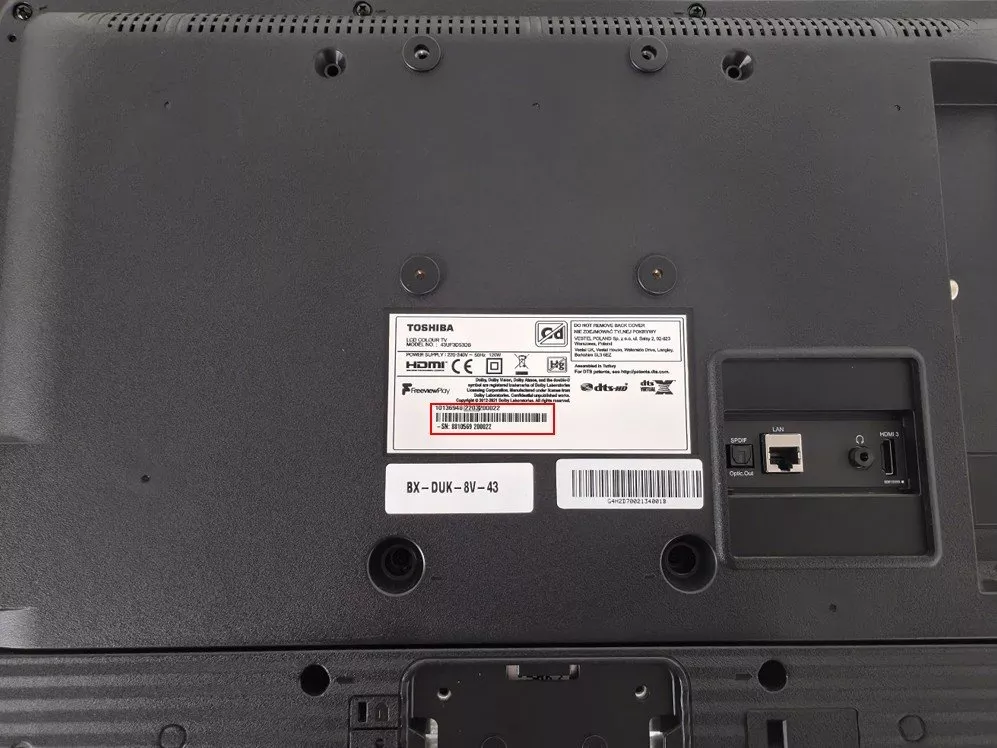 Rear view of Toshiba TV showing model and serial number label, plus HDMI, LAN and optical audio ports.
