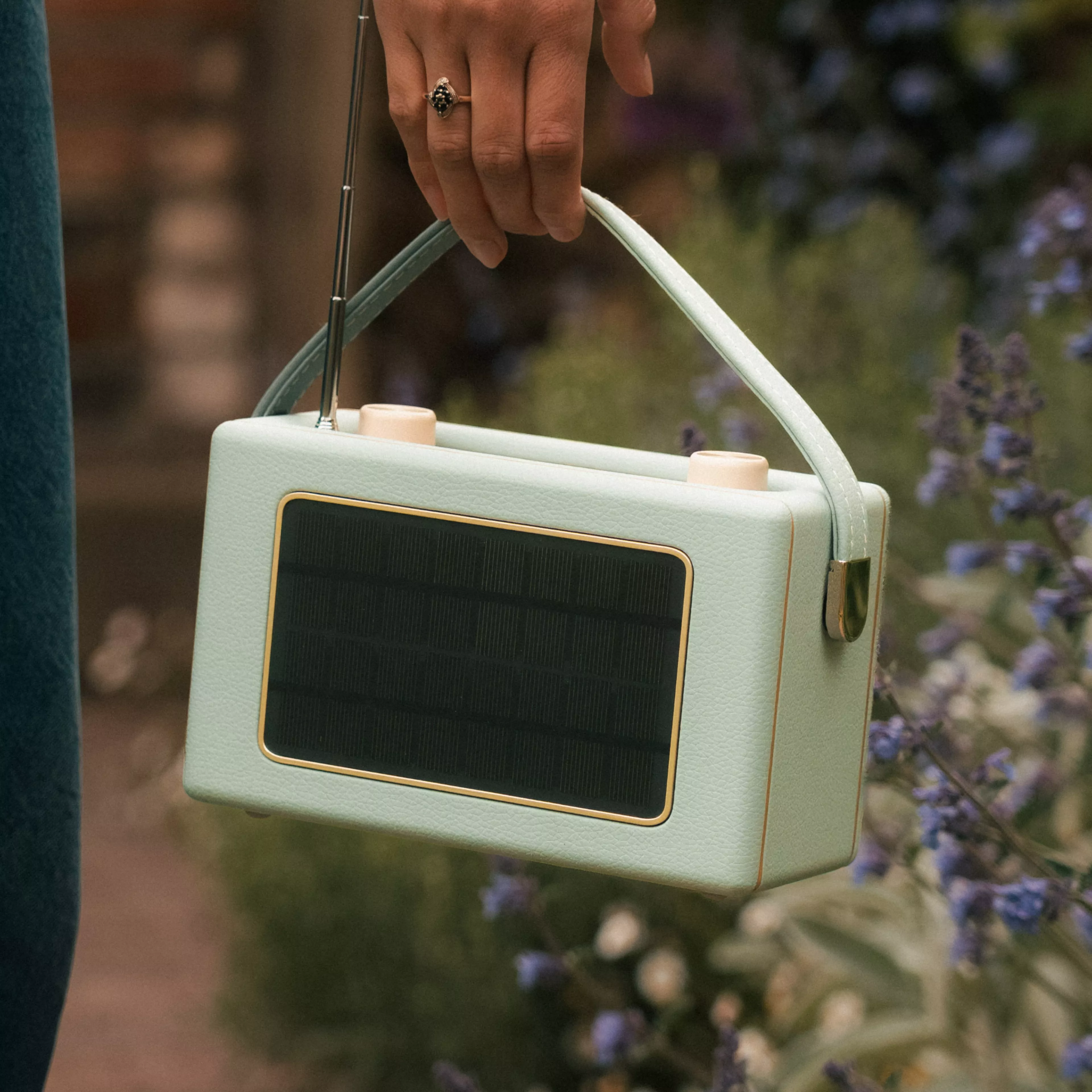 Retro Roberts Bluetooth speaker in pale blue on stacked magazines, cosy living room background with warm firelight