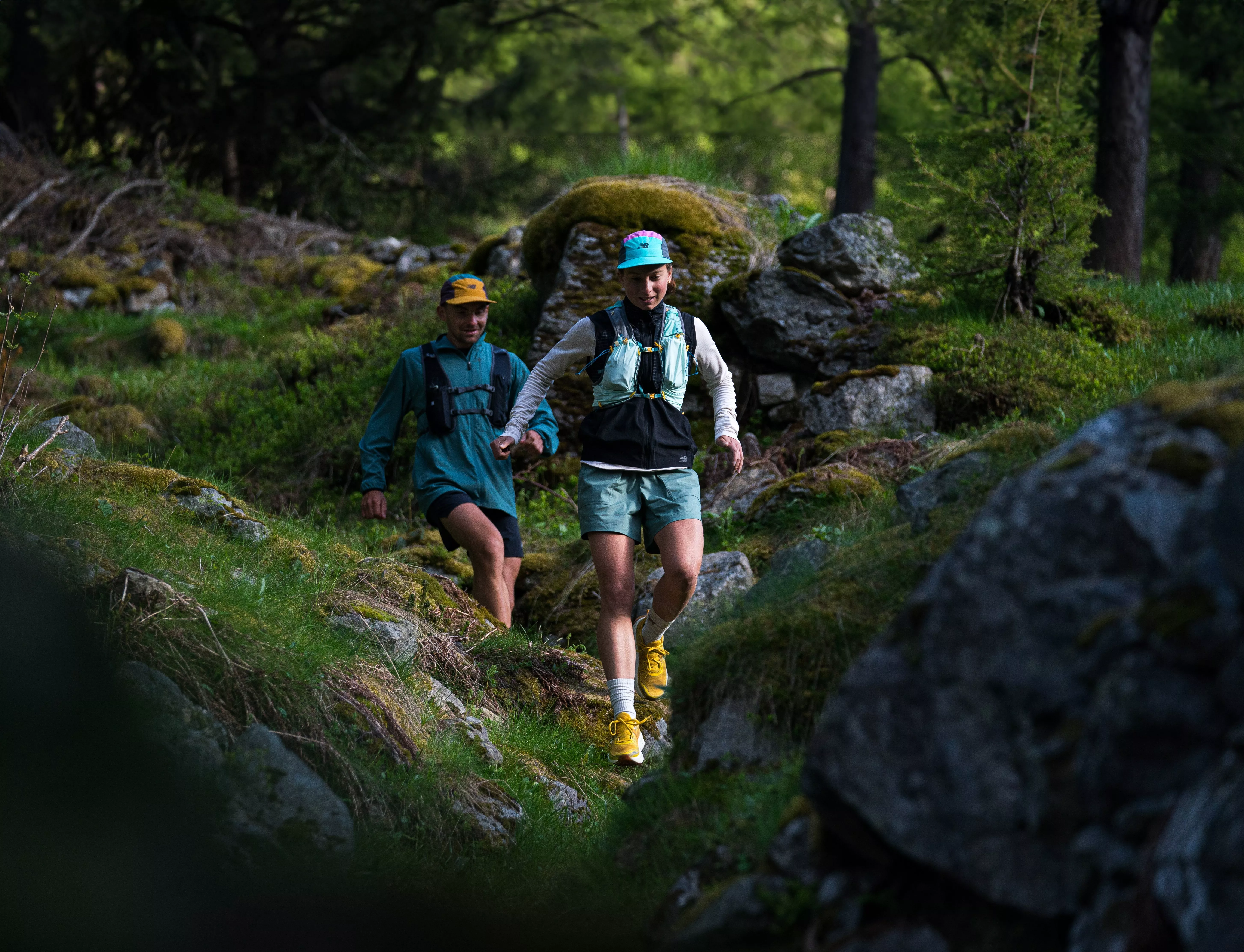 two people hiking through rocky terrain wearing sports clothing