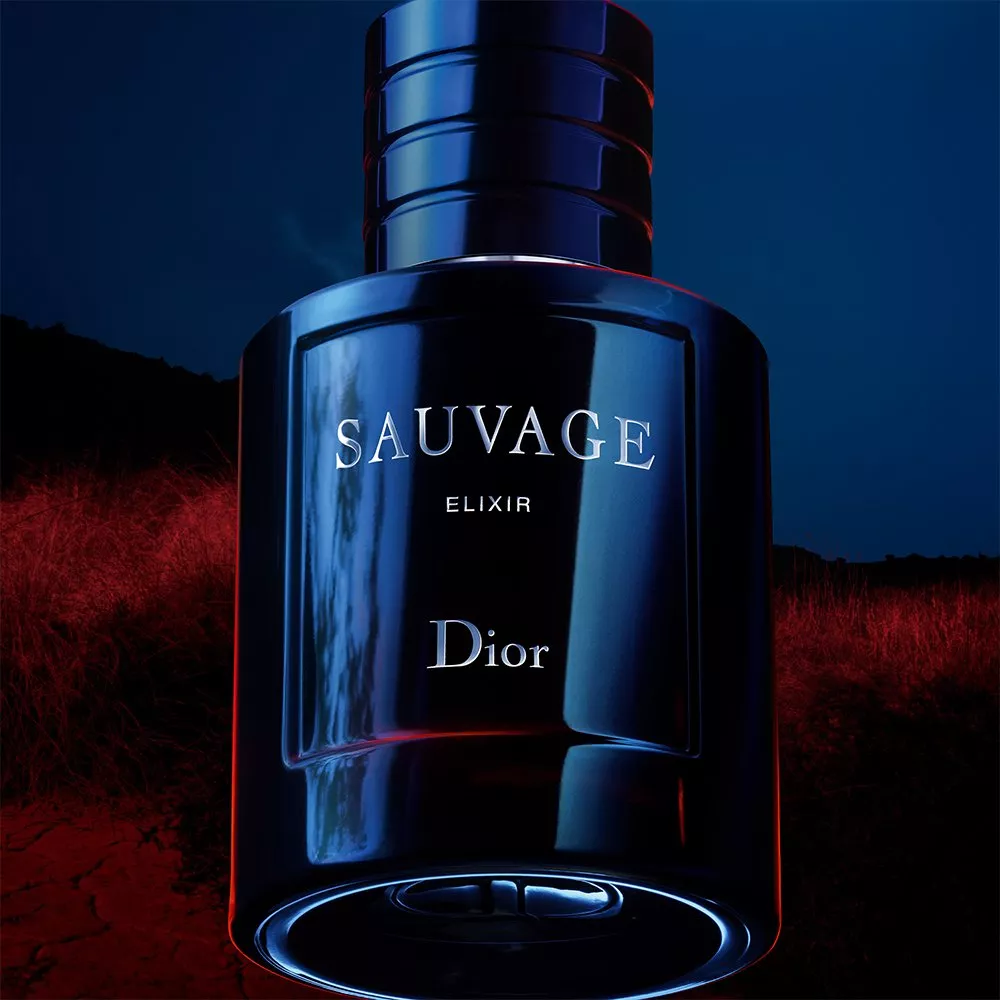Dior Sauvage Elixir aftershave bottle in dark blue glass, close-up fragrance product shot on moody background
