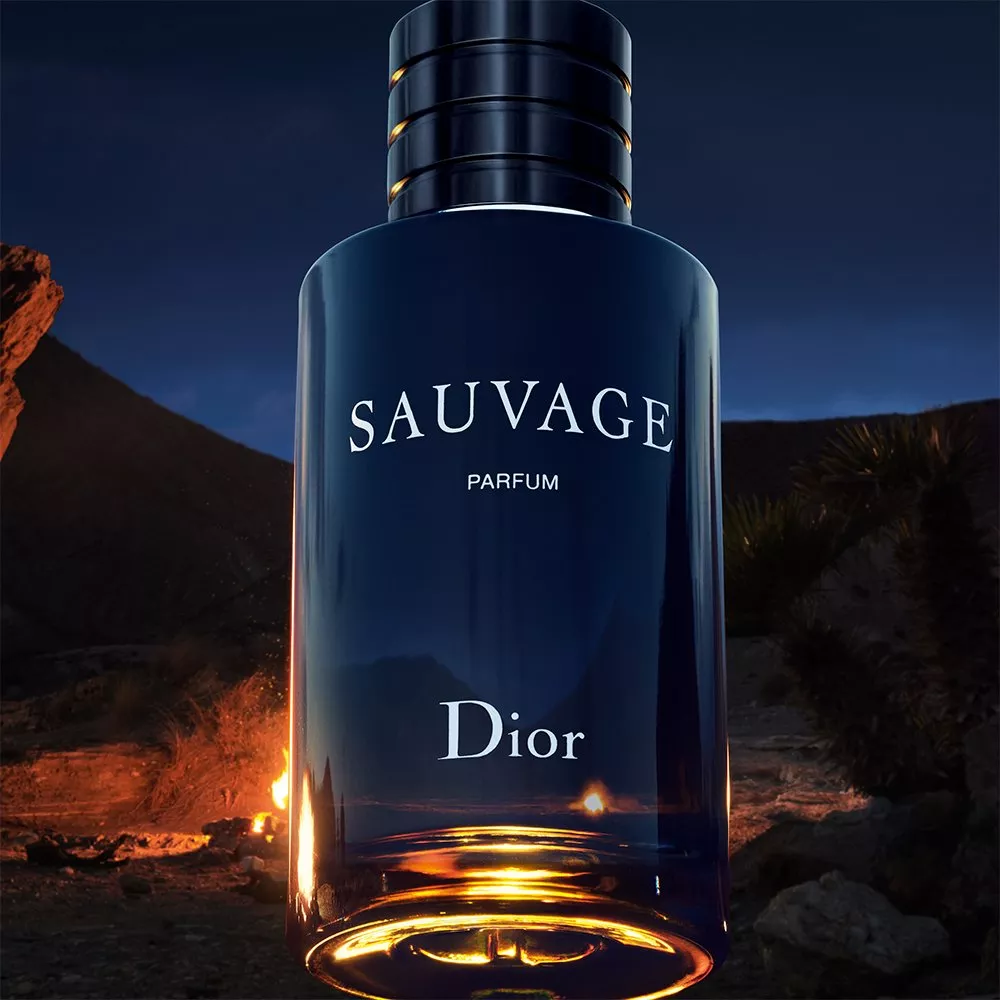 Dior Sauvage Parfum bottle in dark blue glass, product shot with desert night backdrop and warm glow lighting
