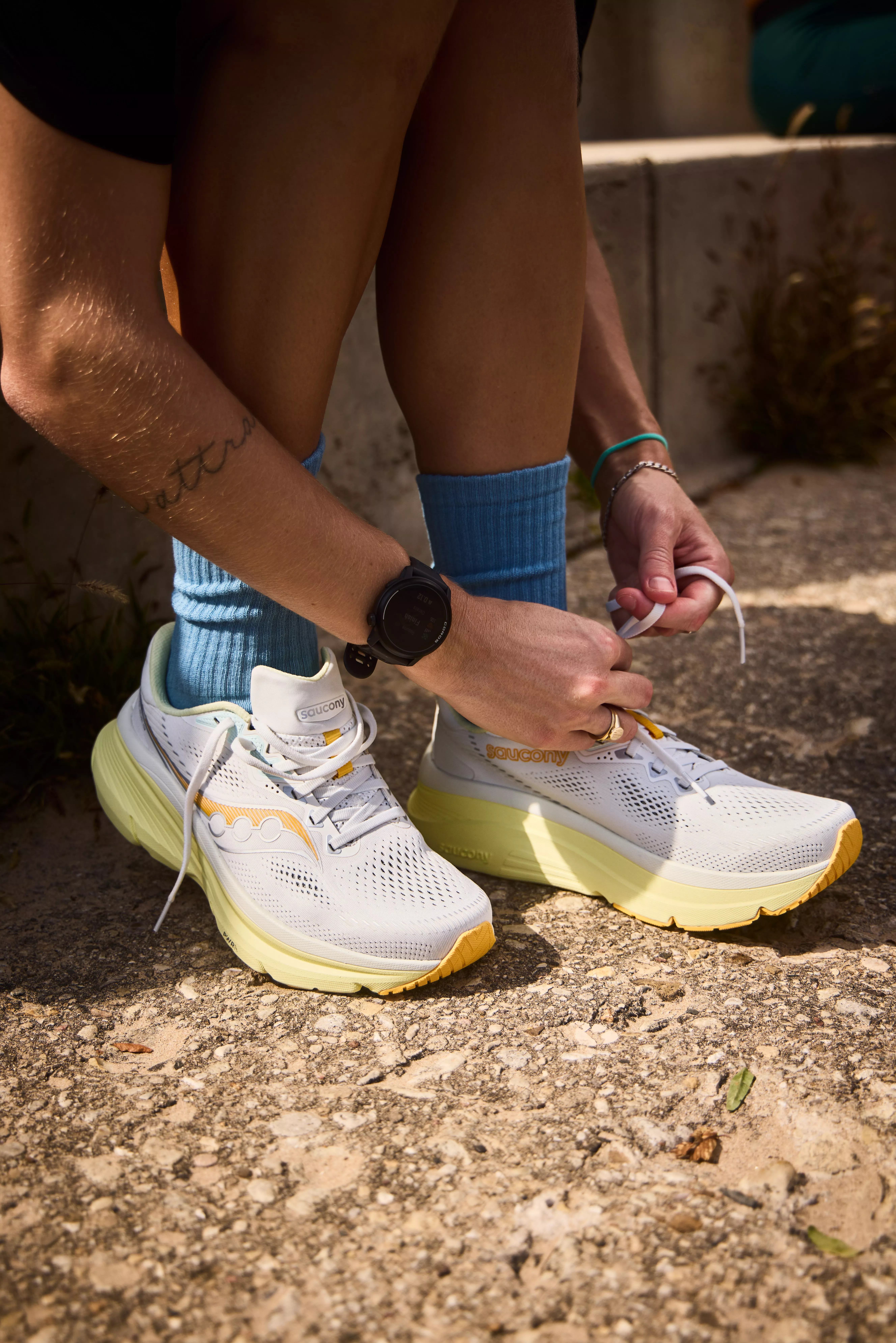 close up of a woman tying up the laces on her saucony running shoes