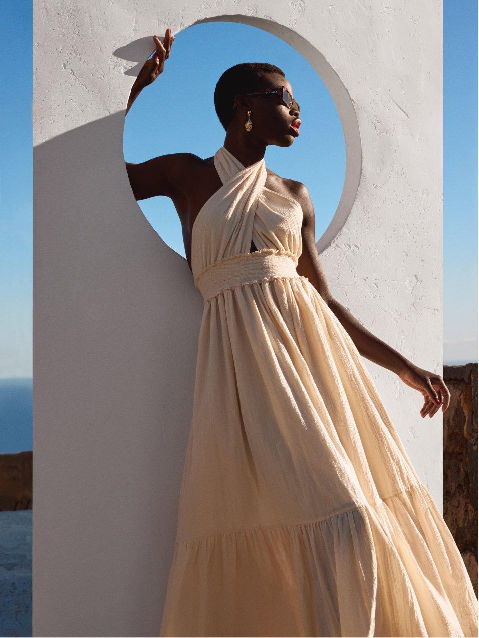 women wearing a cream dress in a window in a sunny landscape