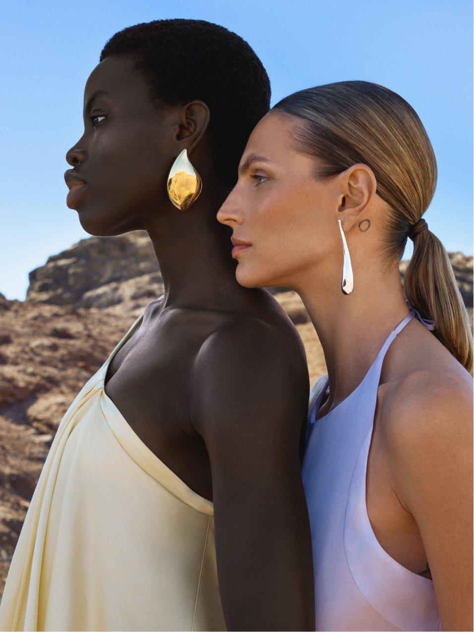 2 women standing next to each other wearing bold jewellery and summer dresses