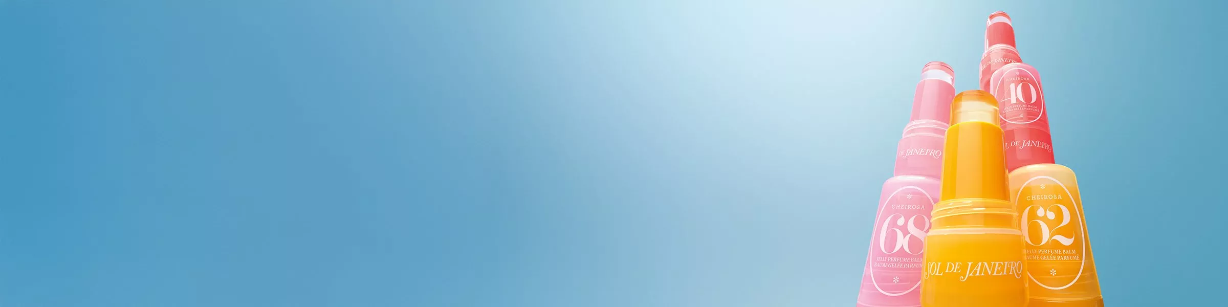 Colourful Sol de Janeiro perfume bottles arranged against a blue gradient background, highlighting vibrant packaging.