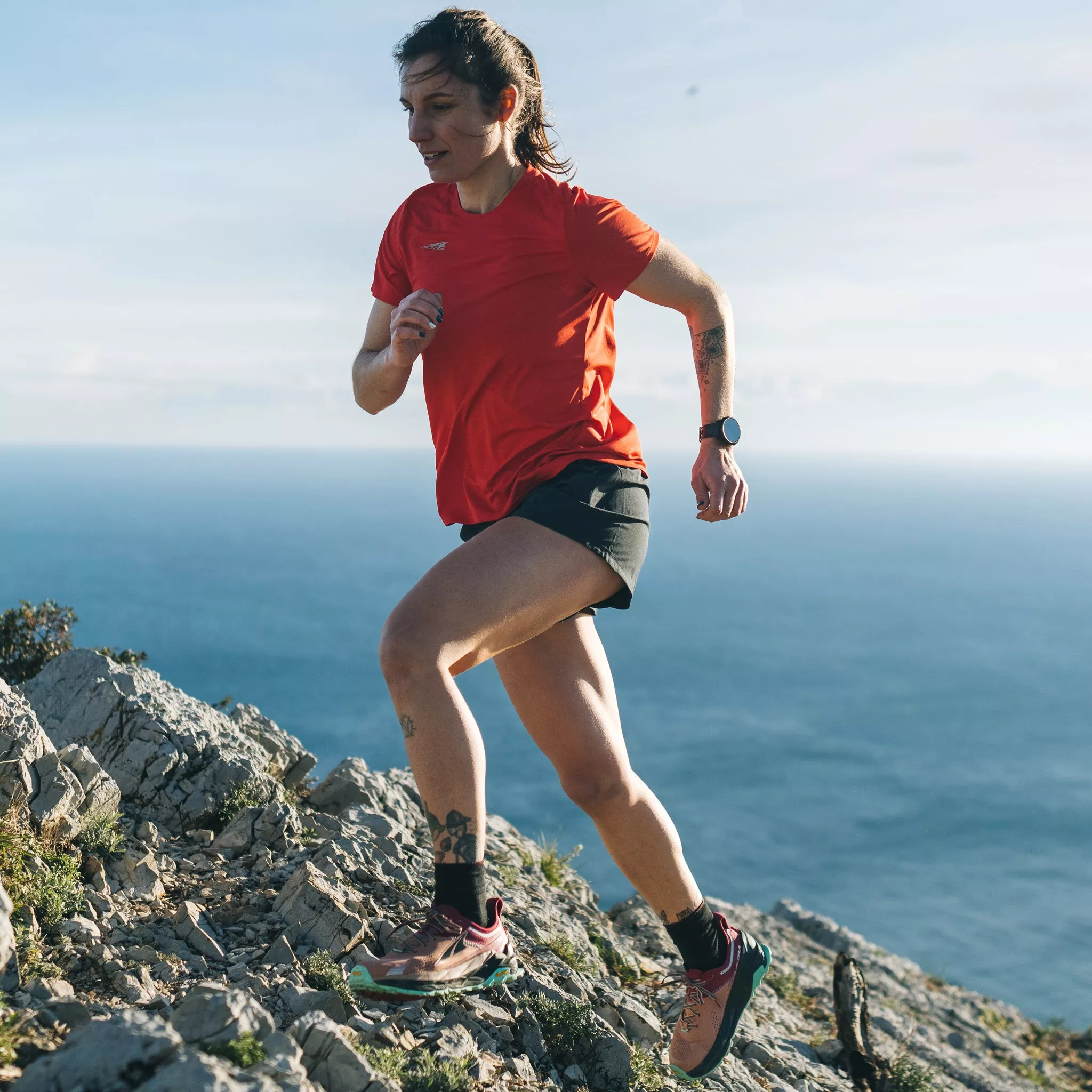 woman running on rocky terrain wearing running apparel