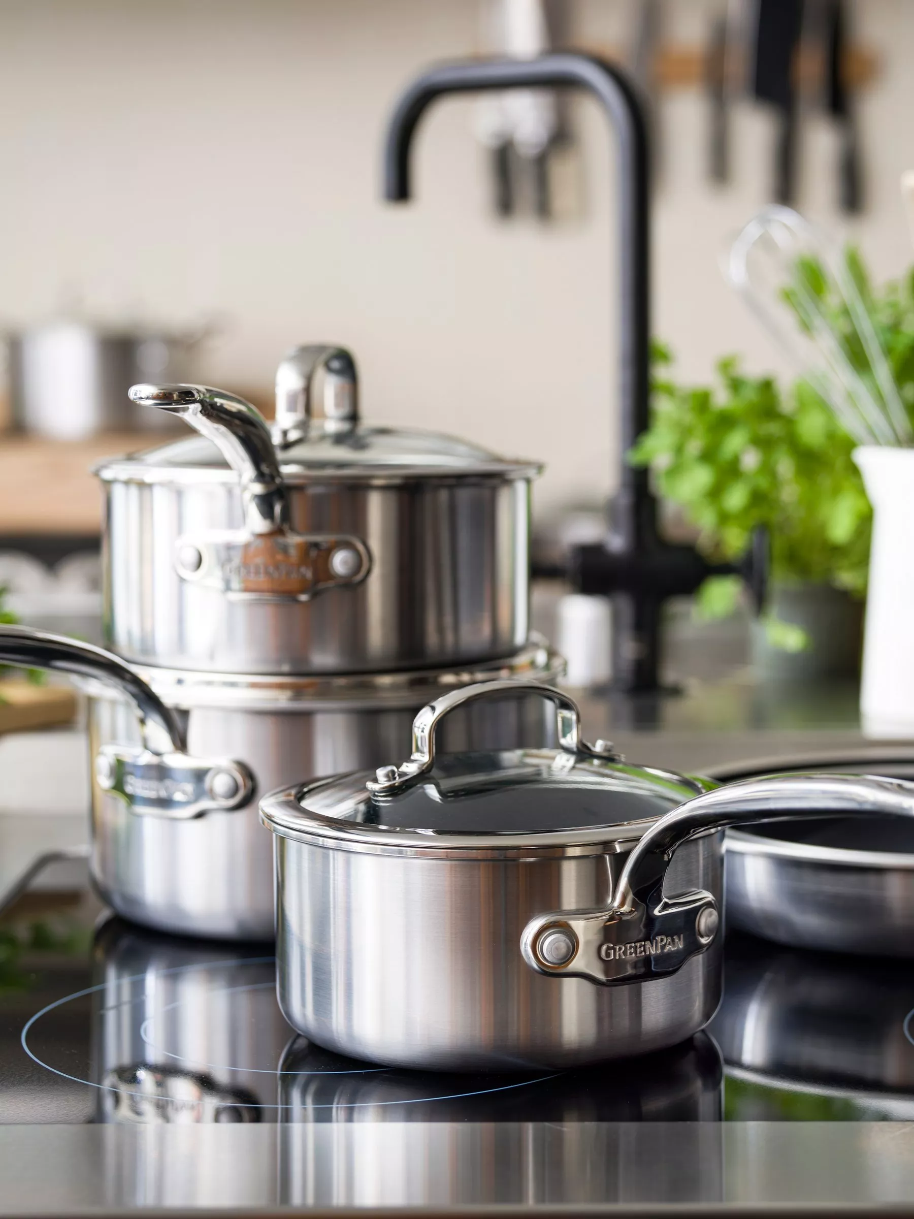 Modern kitchen cookware display with red baking dishes, frying pan, lidded casserole and utensils on worktop