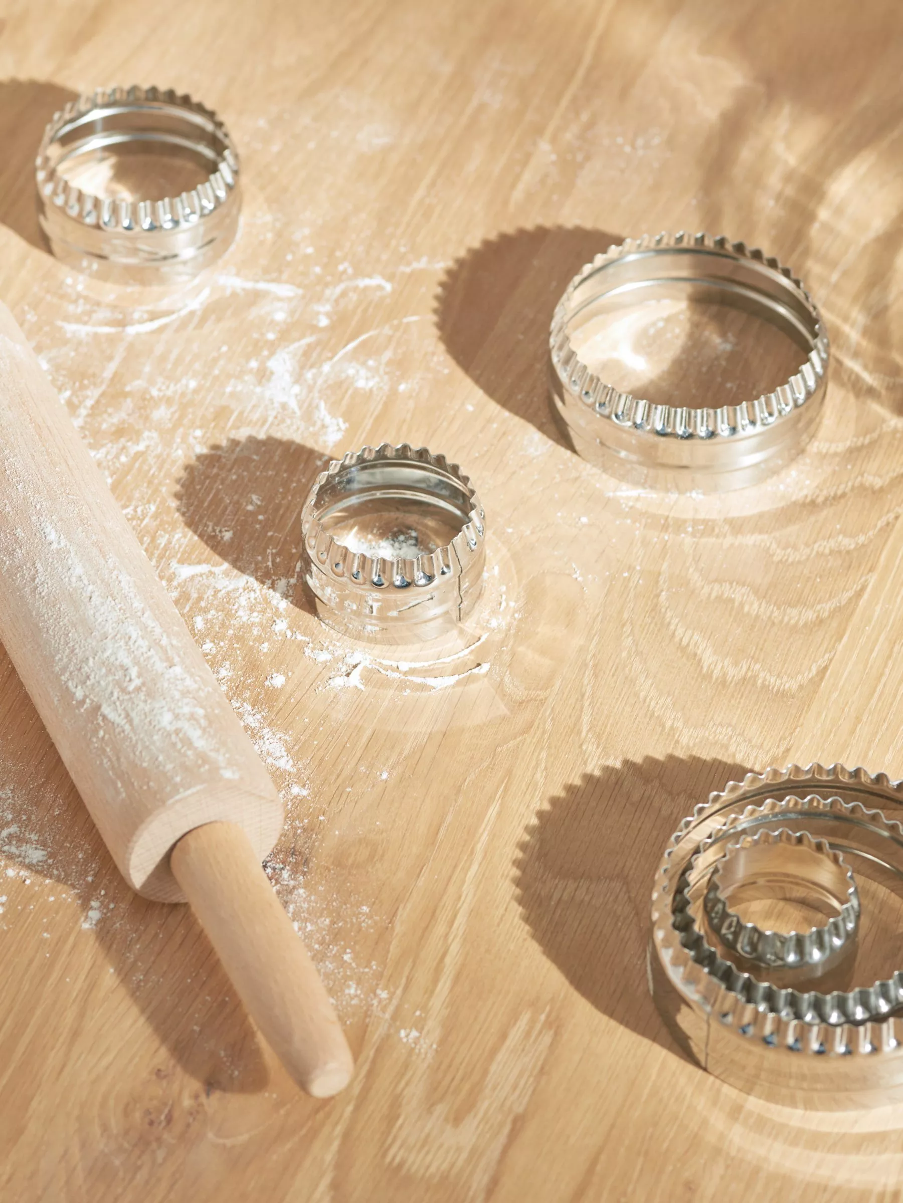 Pastry cutters next to a rolling pin sprinkled with flour