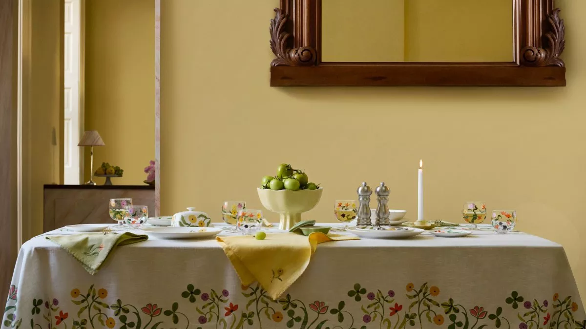 Wooden chair with a floral cushion on wooden flooring, set against a soft yellow wall and white trim.