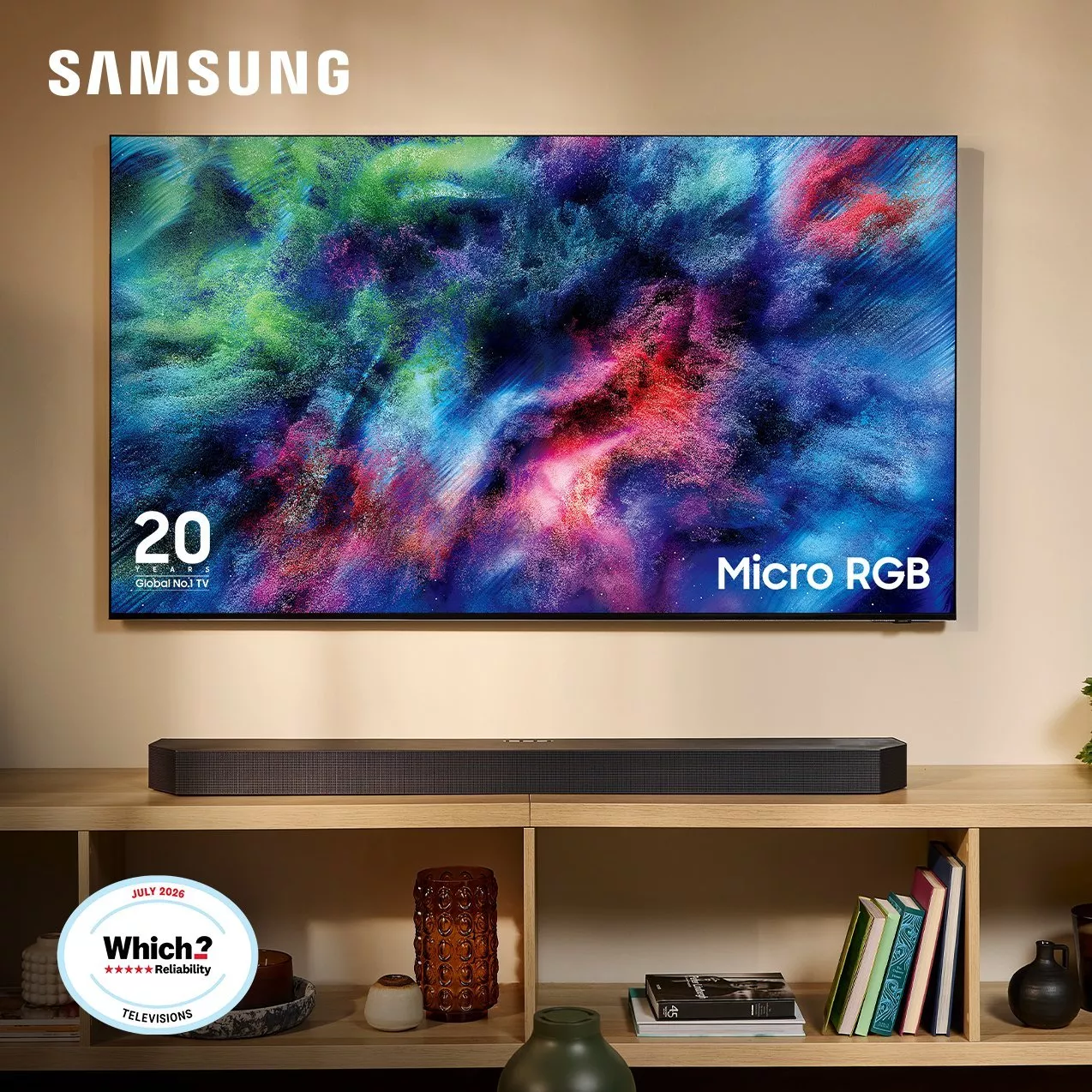 Samsung TV mounted on a wall displaying colorful abstract Micro RGB art above a soundbar on a wooden cabinet. Features "20 Years Global No.1 TV" logo and a July 2026 Which? Reliability badge.