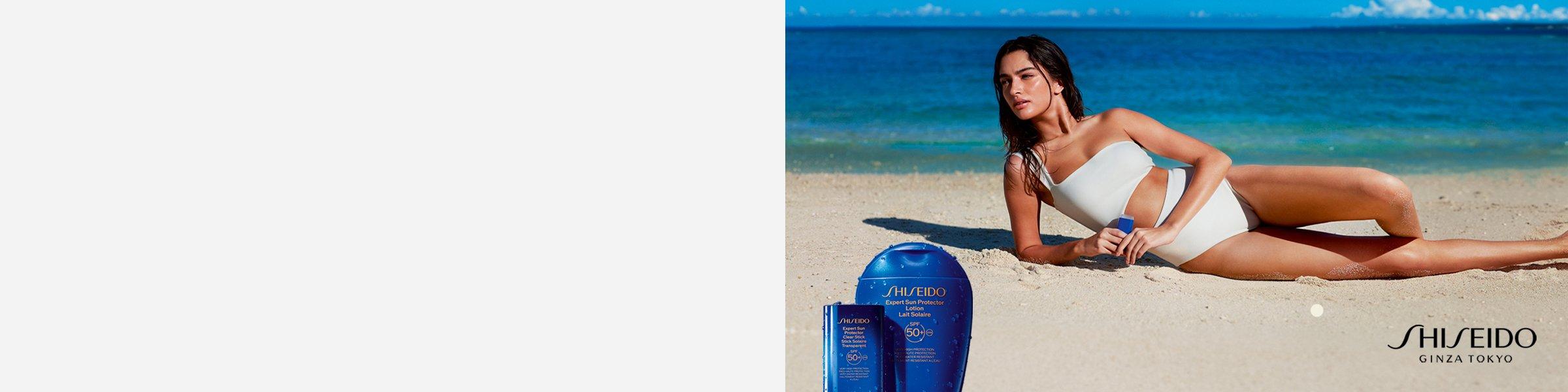 women lying on the beach holding Shiseido skincare