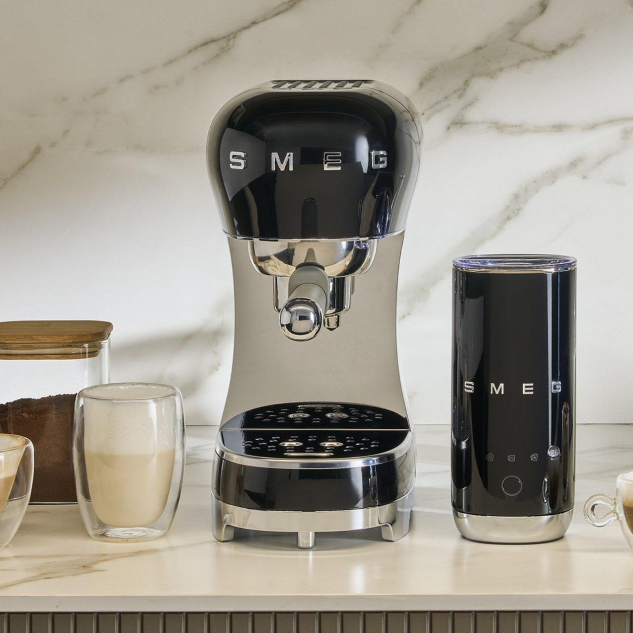 Retro-style Smeg coffee machine on a kitchen countertop alongside a freshly brewed cup of coffee